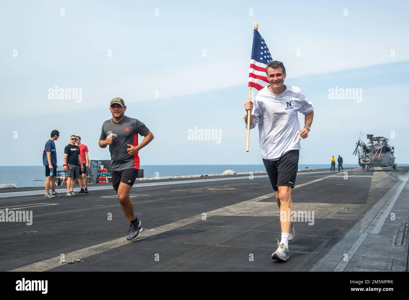 220327-N-TO573-1010 MER ADRIATIQUE (27 mars 2022) le commandant du Carrier Strike Group 8, l'ADM. Curt Renshaw, arrière, court avec l'ensign des États-Unis au cours d'une course et d'une rangée de 5 kilomètres sur le pont de vol du porte-avions de la classe Nimitz USS Harry S. Truman (CVN 75), 27 mars 2022. Le groupe de grève des transporteurs Harry S. Truman est en cours de déploiement aux États-Unis Sixième zone d'exploitation de la flotte à l'appui des intérêts des États-Unis, des alliés et des partenaires en Europe et en Afrique. Banque D'Images