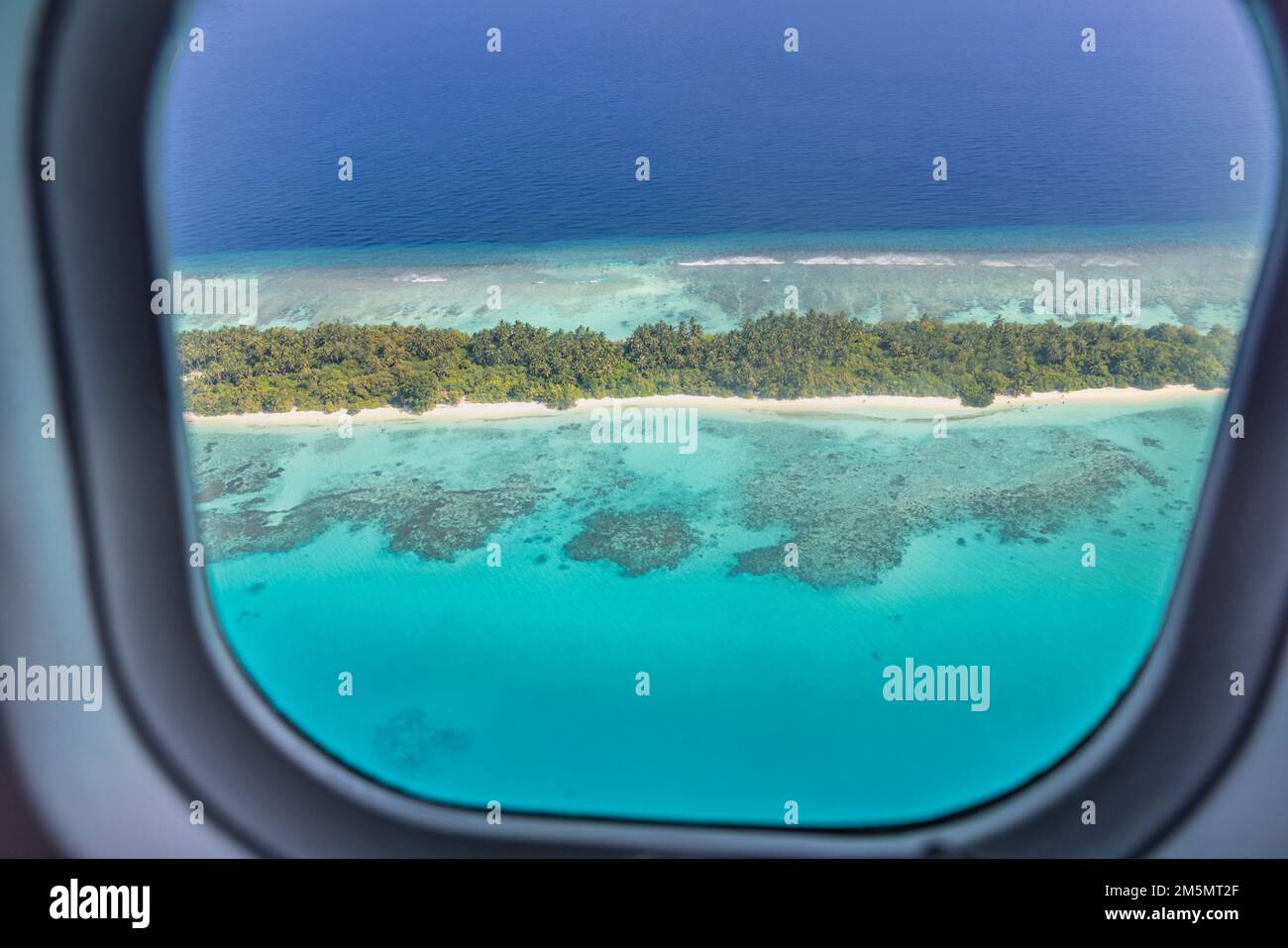 Fenêtre d'avion avec belle vue sur l'île des Maldives. Vacances d'été de luxe voyage tourisme fond, vue de la fenêtre d'avion. Îles atolls Banque D'Images