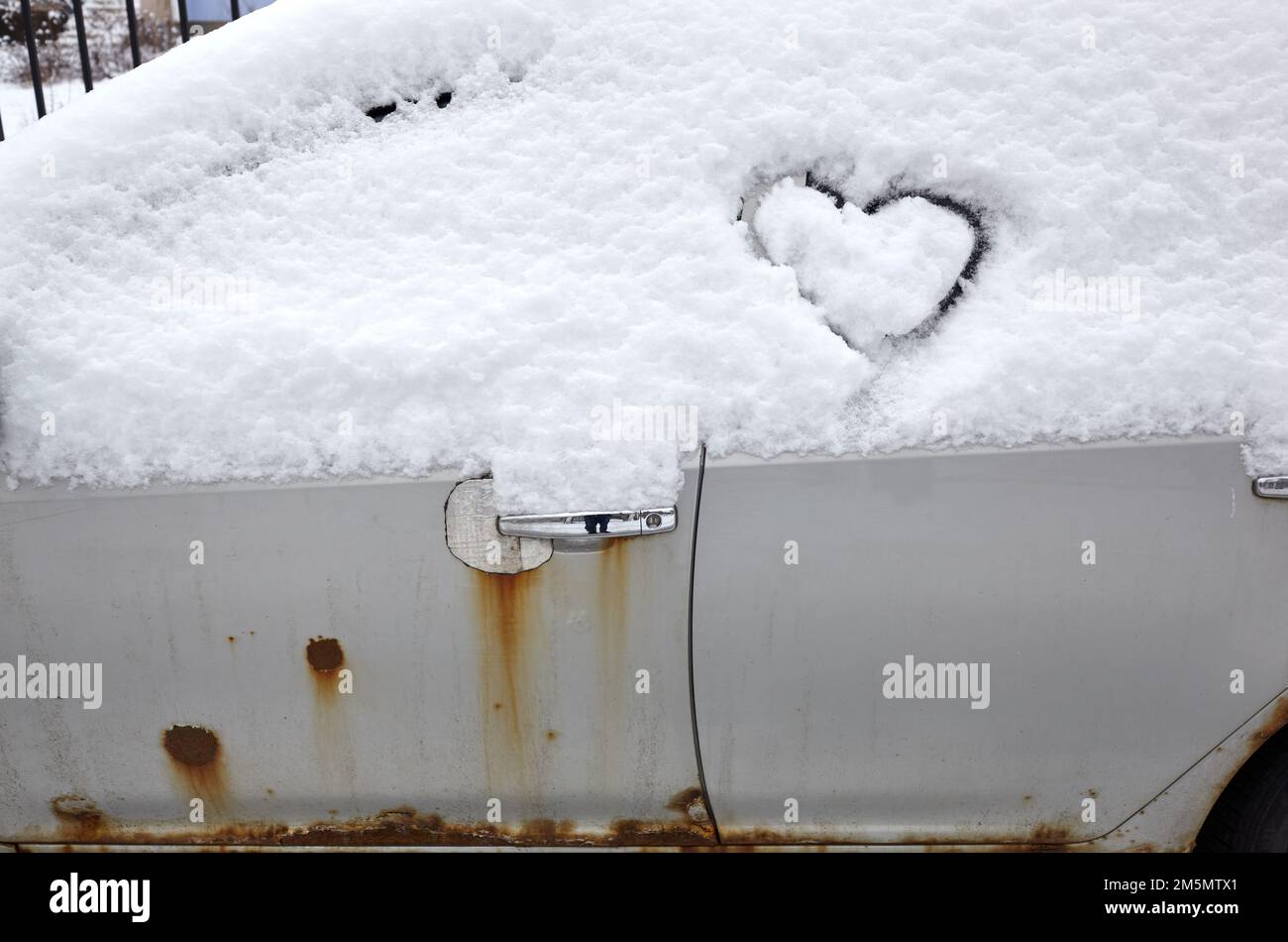 Signe d'amour en forme de coeur, dessiné sur une voiture enneigée. Forme de coeur dessinée à la main dans la neige fraîche. Symbole de l'amour en hiver Banque D'Images