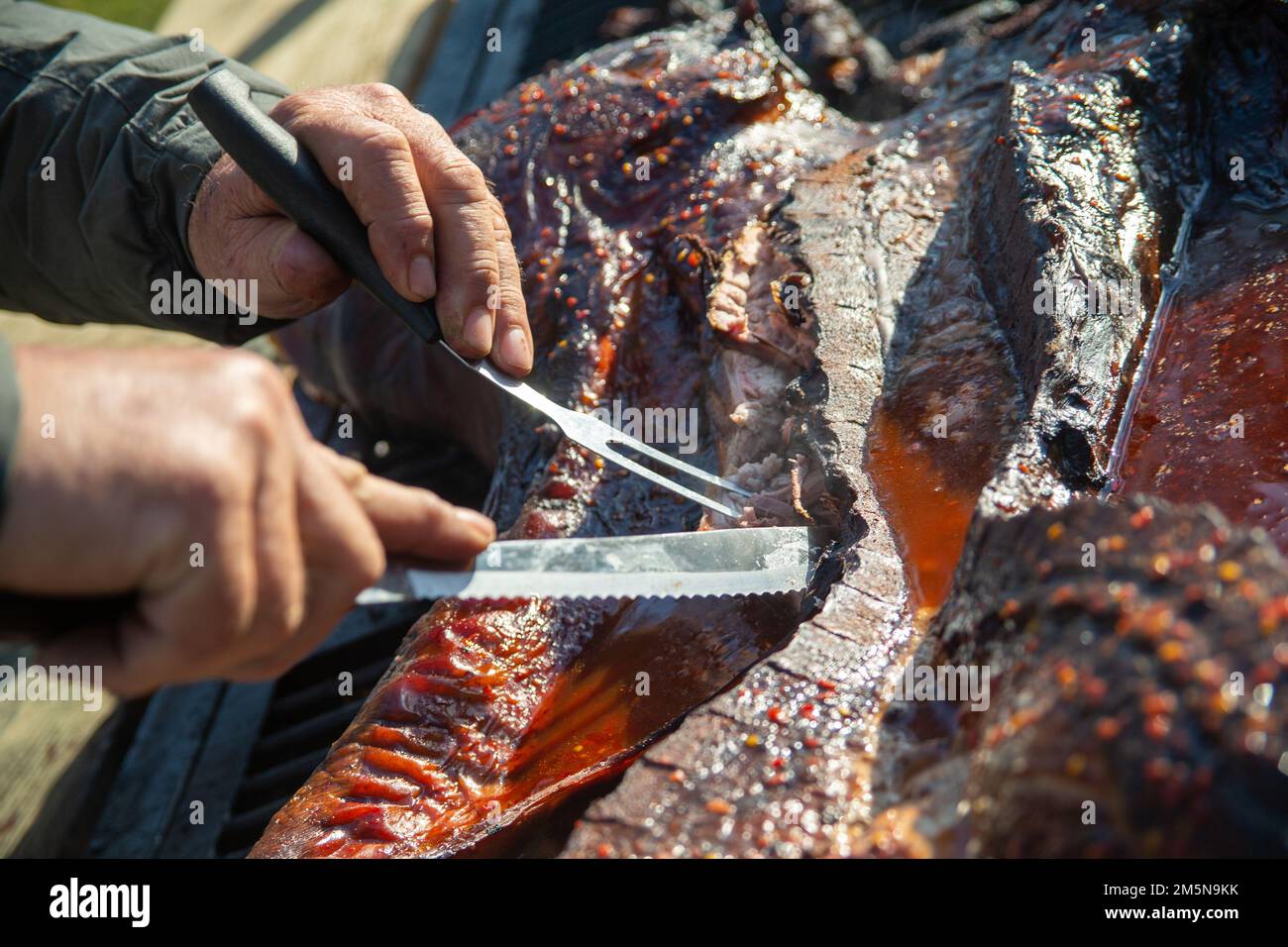 Gary Baldree, un bénévole du Pig Pickin', coupe un cochon rôti au Hancock Lodge, à la station aérienne du corps des Marines Cherry point, en Caroline du Nord, en 29 mars 2022. Chaque printemps et chaque automne, la Commission des affaires militaires (MAC) de la Chambre de commerce de Havelock réunit un Pig Pickin' pour accueillir les Marines stationnées à MCAS Cherry point dans la communauté. Banque D'Images