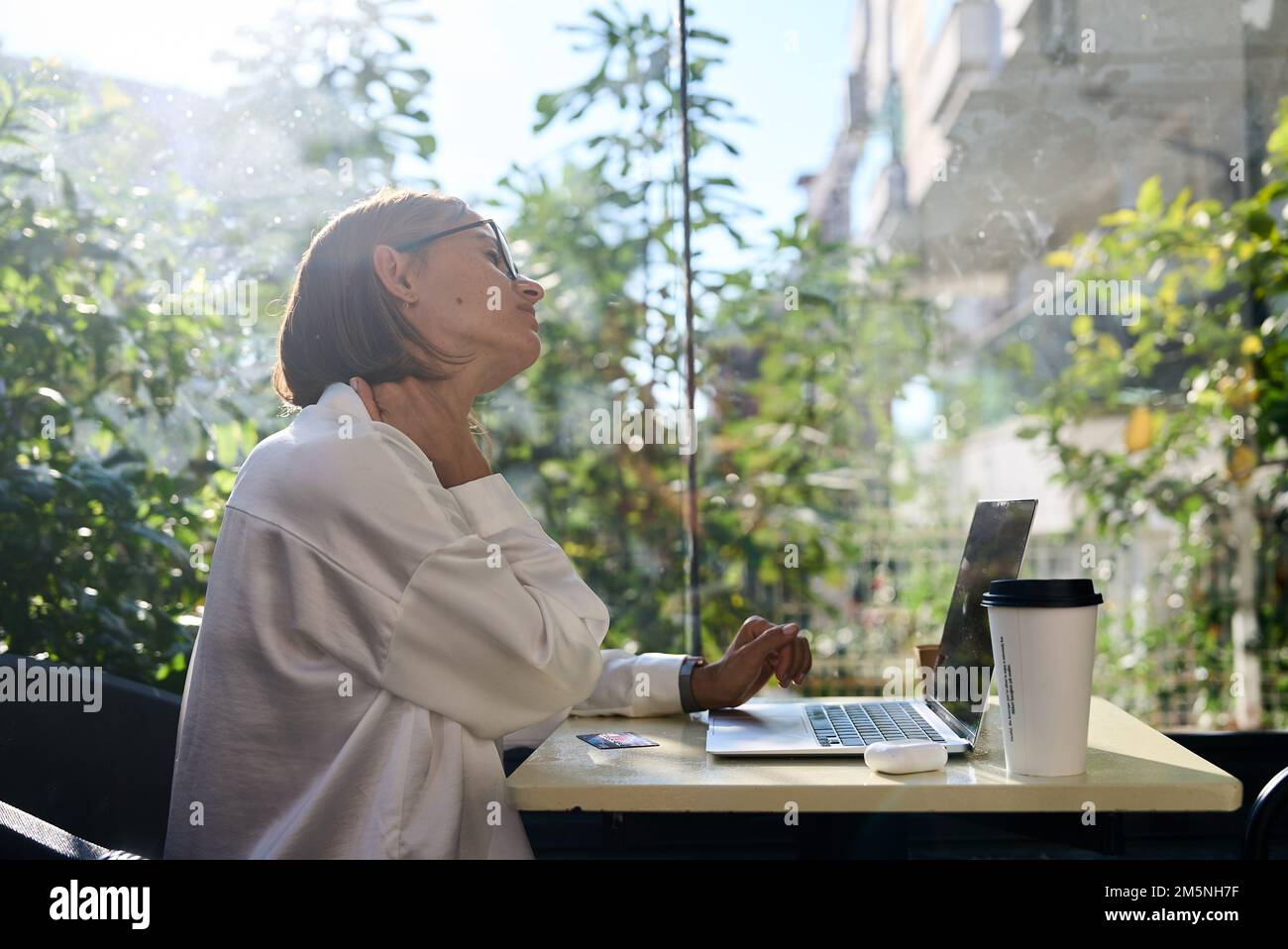 Femme fatiguée stressée souffrant de douleurs au cou travaillant à la maison de bureau assis à table. Femme trop travaillée, jeune âge, massant le cou, sensation de douleur Banque D'Images