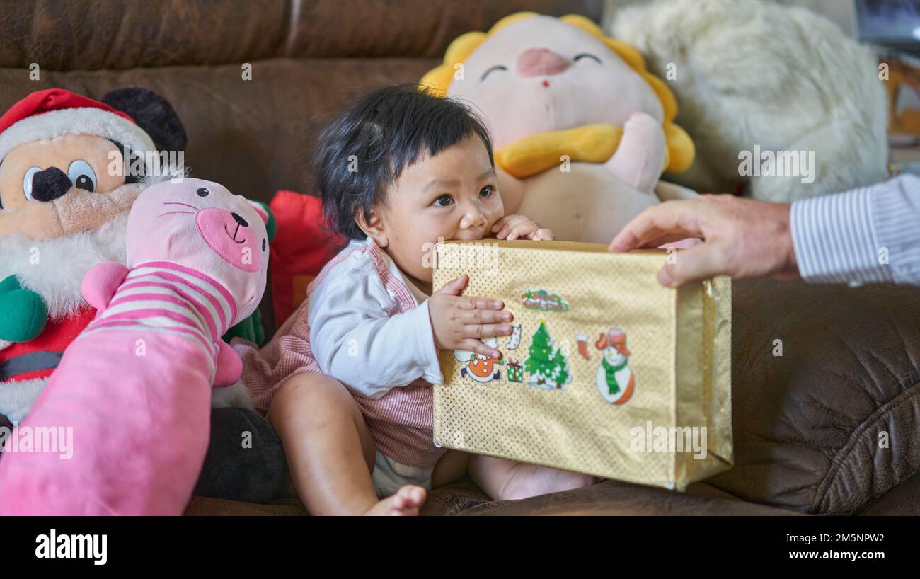 Un petit bébé heureux reçoit son premier cadeau de Noël. Banque D'Images