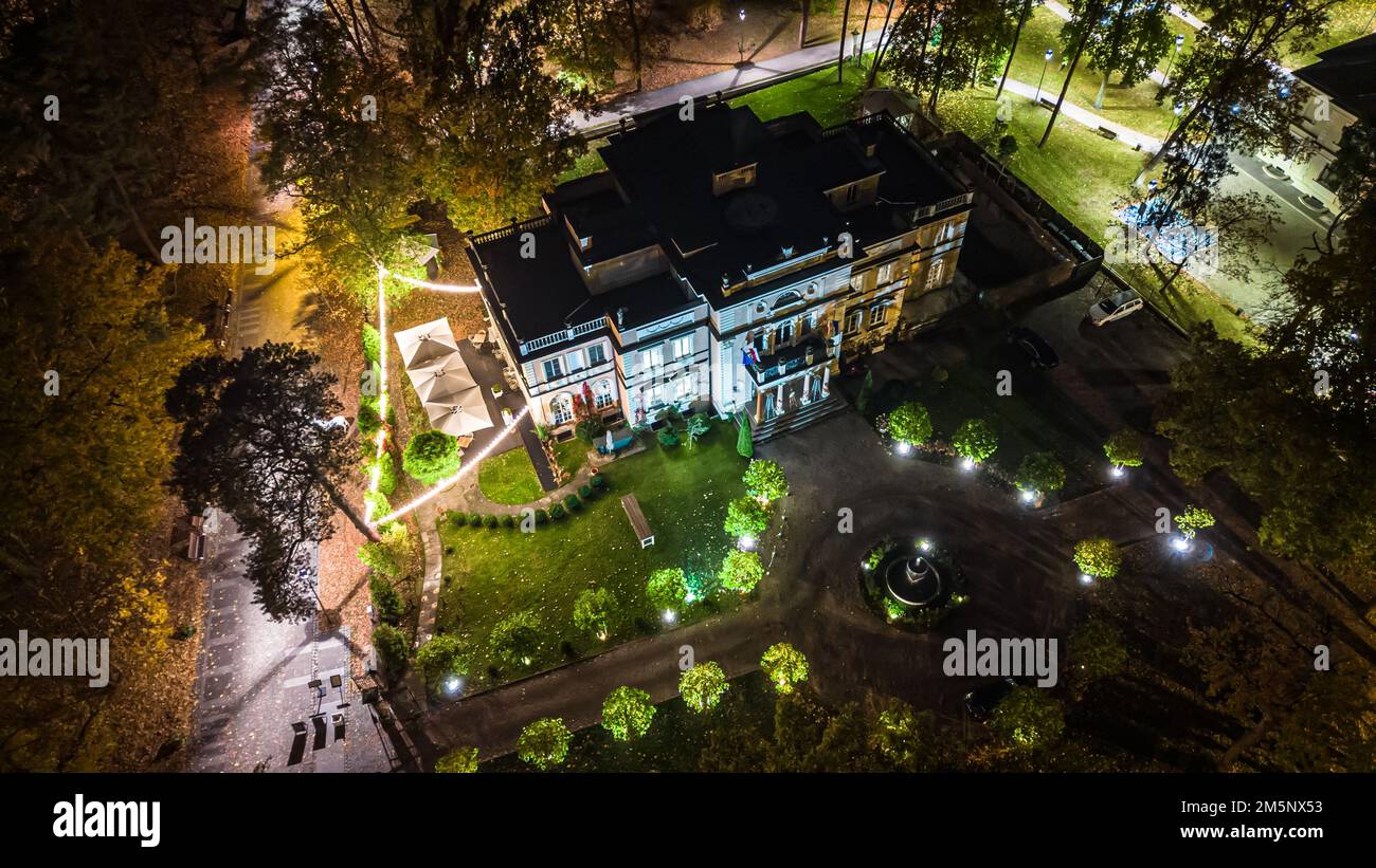 Vue nocturne sur un café du complexe ou un restaurant avec parasols, tables et chaises, bar vide entouré d'arbres éclairés Banque D'Images