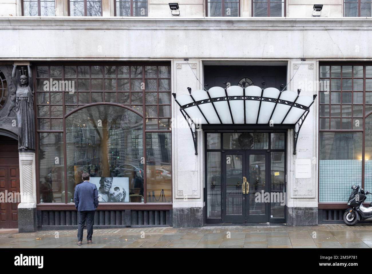 Un homme regarde un diaporama d'images montrant le footballeur Pele dans la fenêtre de l'ambassade du Brésil à Londres à la suite de la mort du trois fois vainqueur de la coupe du monde jeudi à Sao Paulo.Date de la photo : vendredi 30 décembre 2022. Banque D'Images