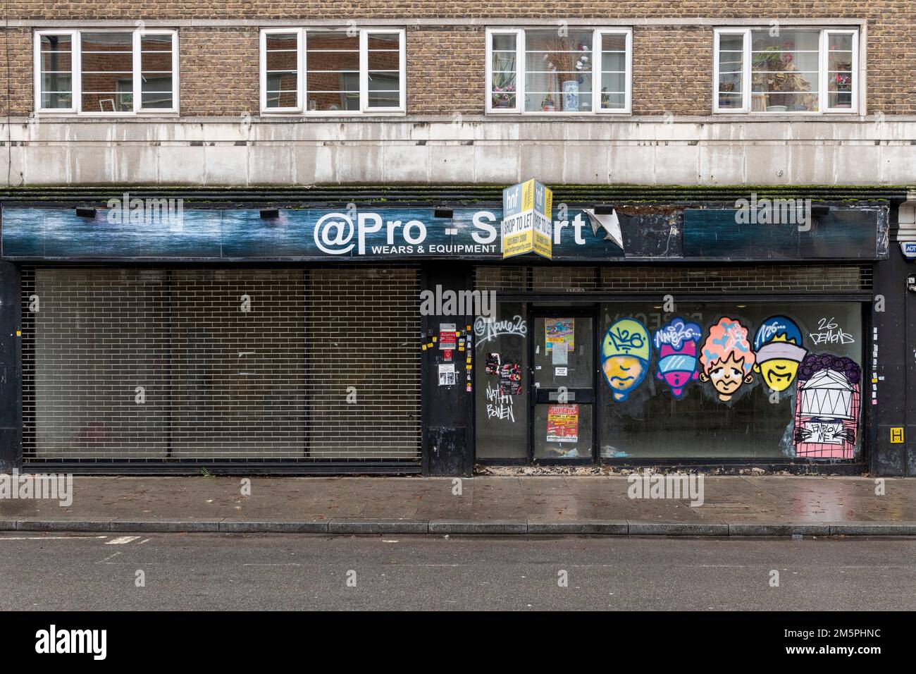 Une boutique fermée avec des affiches d'art de rue à pâte de blé sur ses fenêtres, Kirkdale, Londres, Royaume-Uni. 25 décembre 2022 Banque D'Images