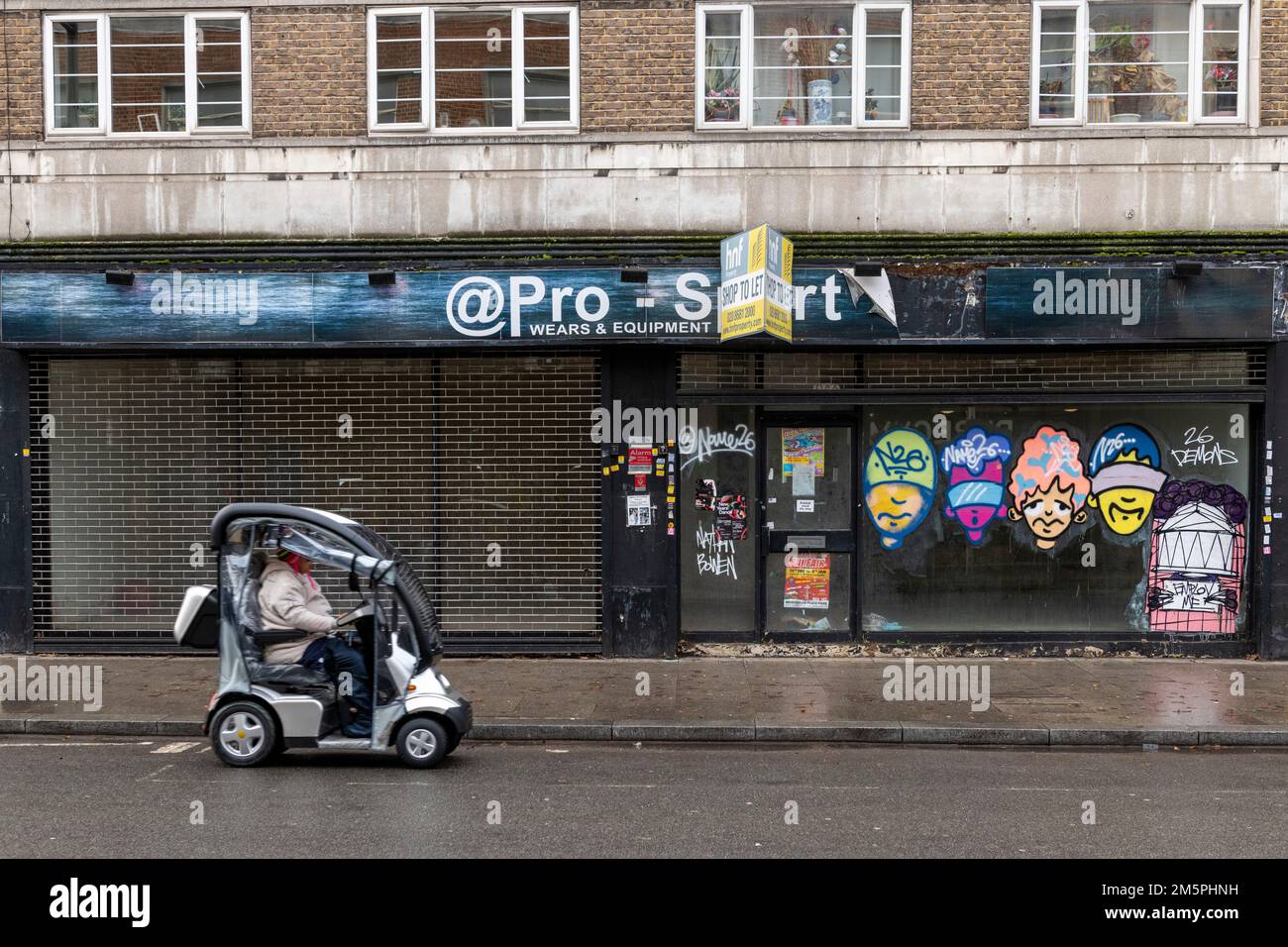 Une boutique fermée avec des affiches d'art de rue à pâte de blé sur ses fenêtres, Kirkdale, Londres, Royaume-Uni. 25 décembre 2022 Banque D'Images