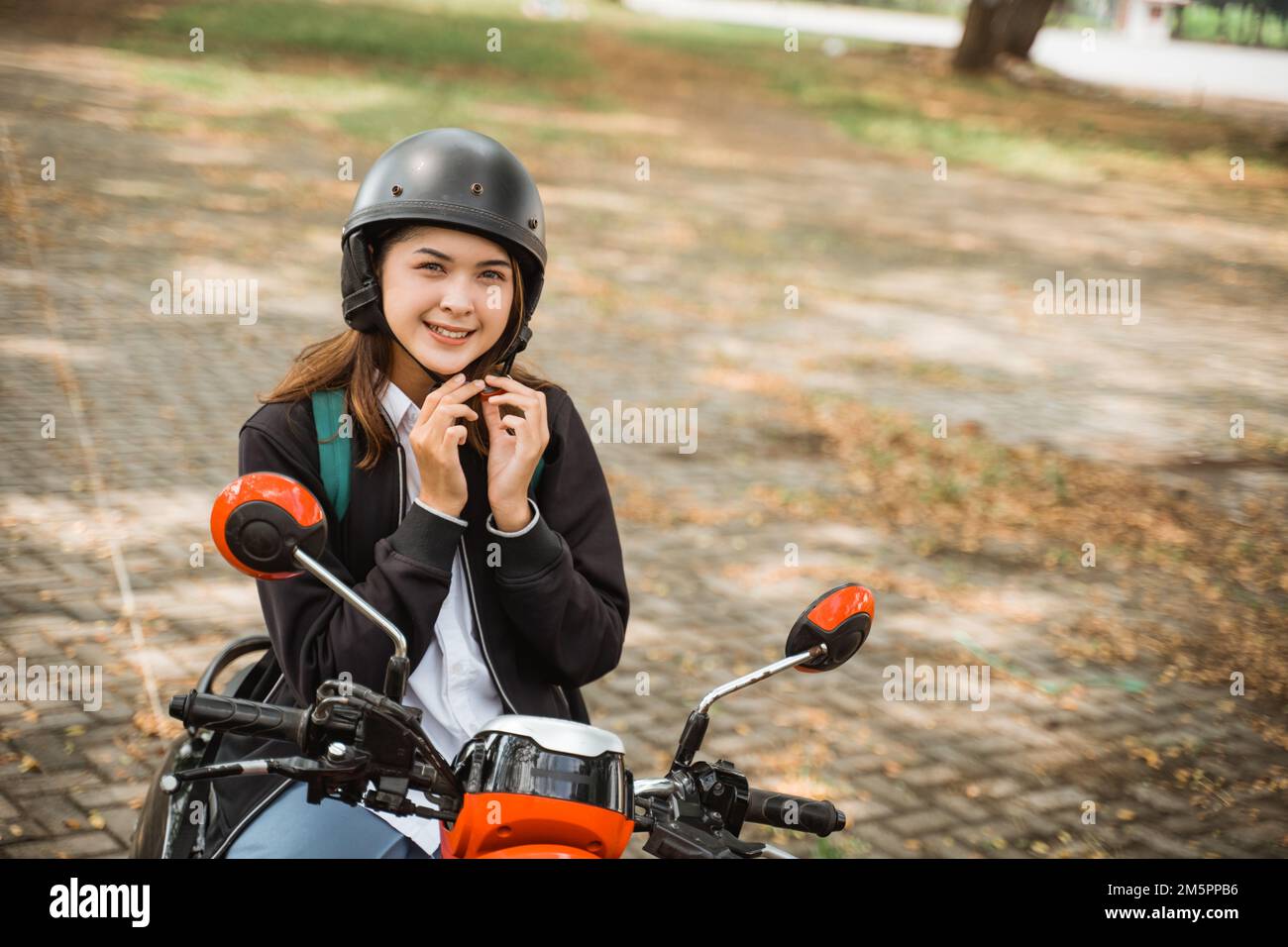 Une jeune fille qui porte une sangle de casque est en moto pour aller à  l'école Photo Stock - Alamy