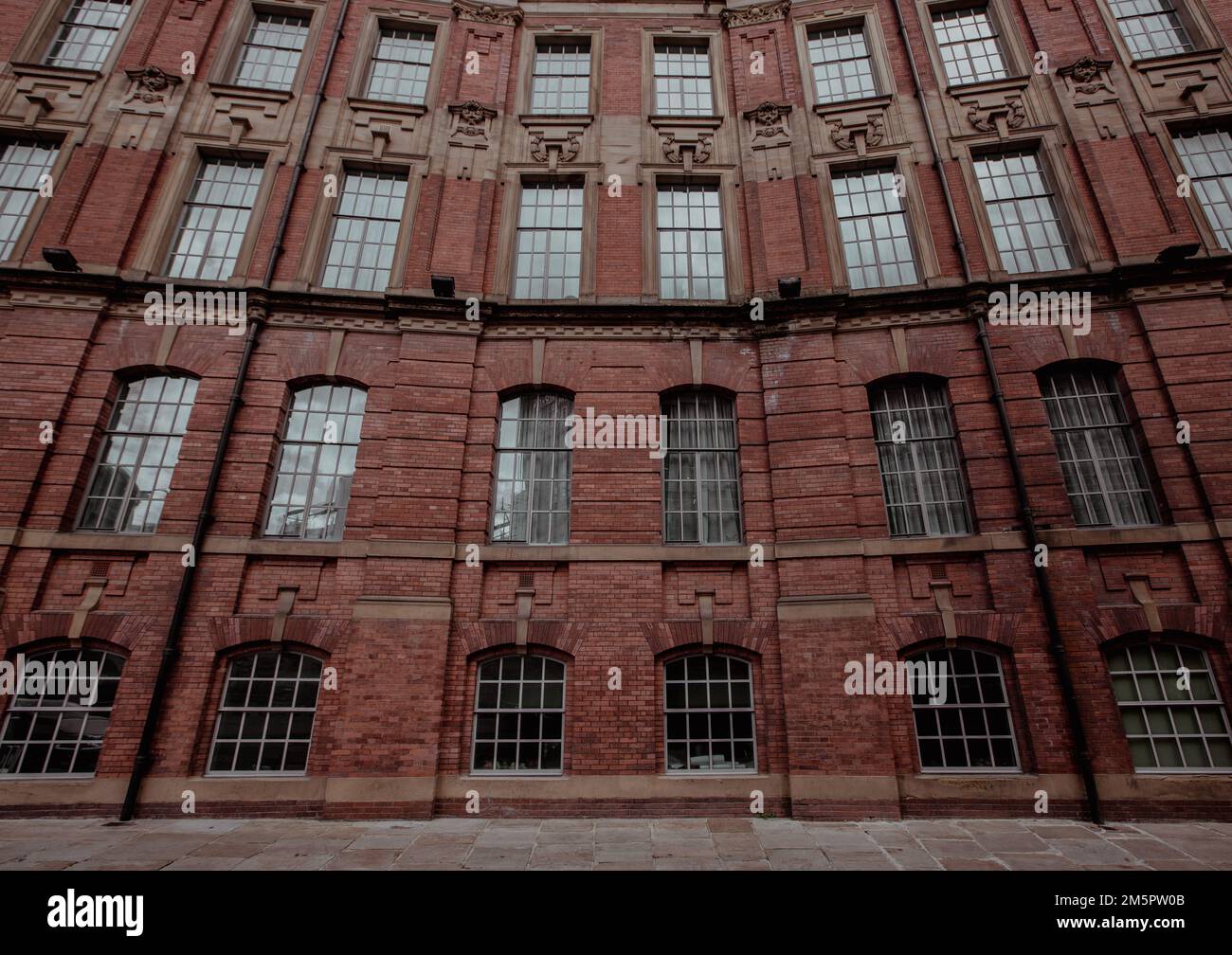 Vue panoramique sur un imposant bâtiment victorien en briques rouges et rangées de cadres de fenêtres ornés et architecture avec espace de copie Banque D'Images