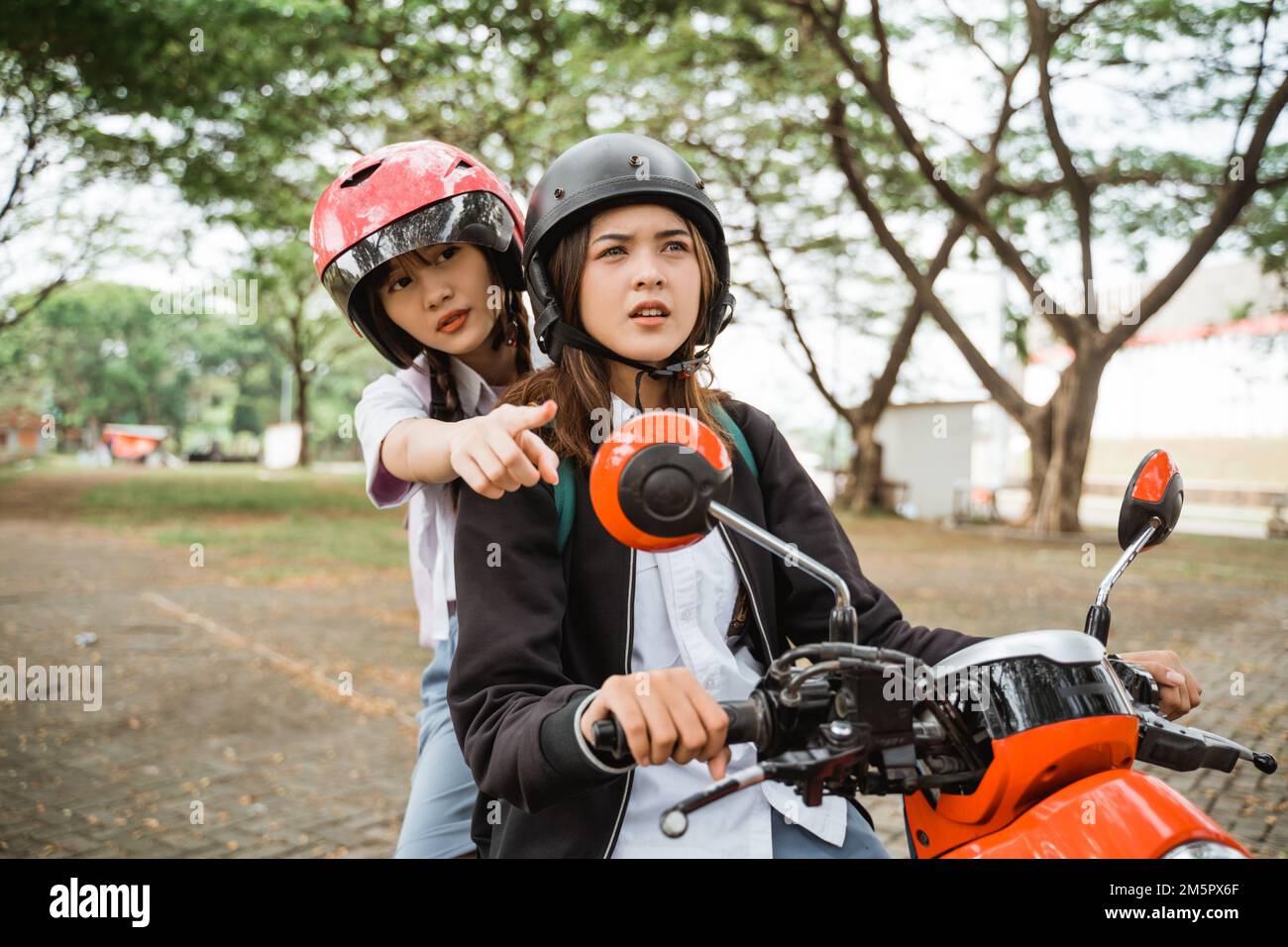 Des amis qui pointent sur la voie lorsque vous conduisez une moto après l'école Banque D'Images