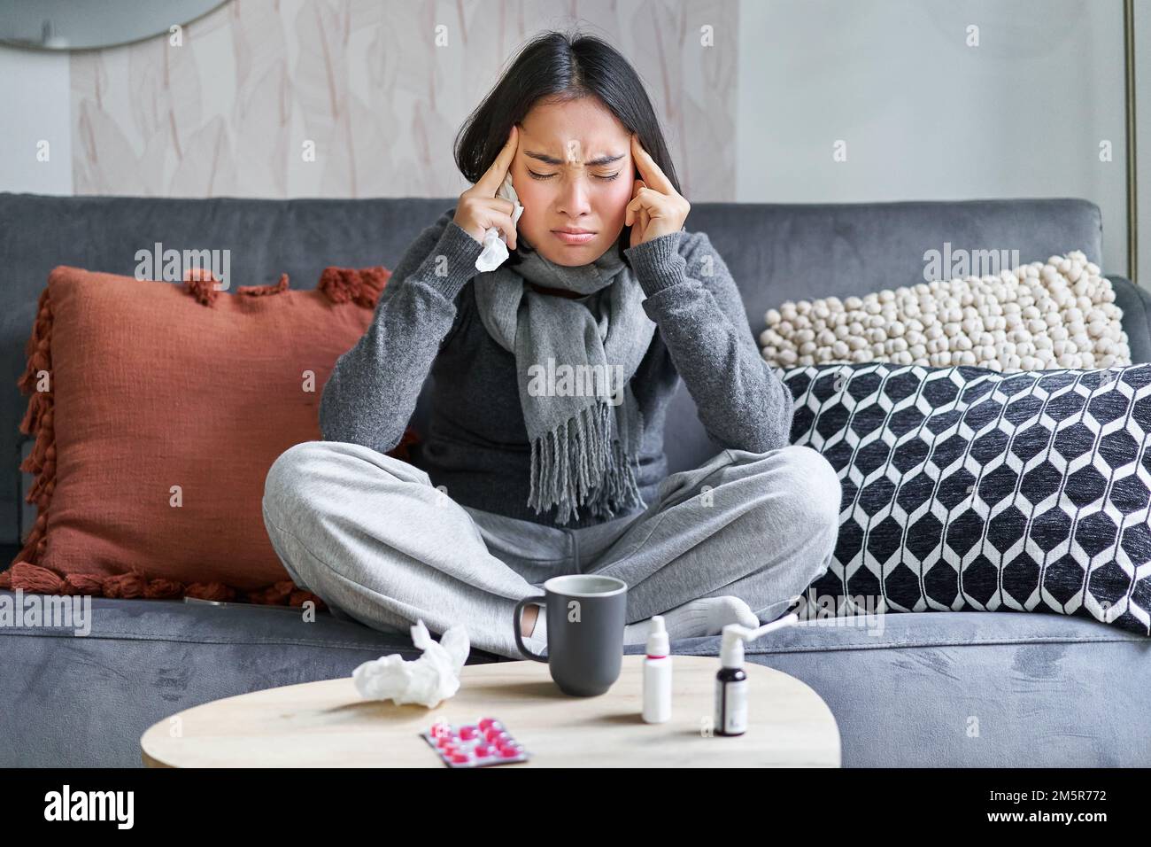 La jeune femme asiatique se sent mal, touche la tête, a des maux de tête et de la fièvre, rester