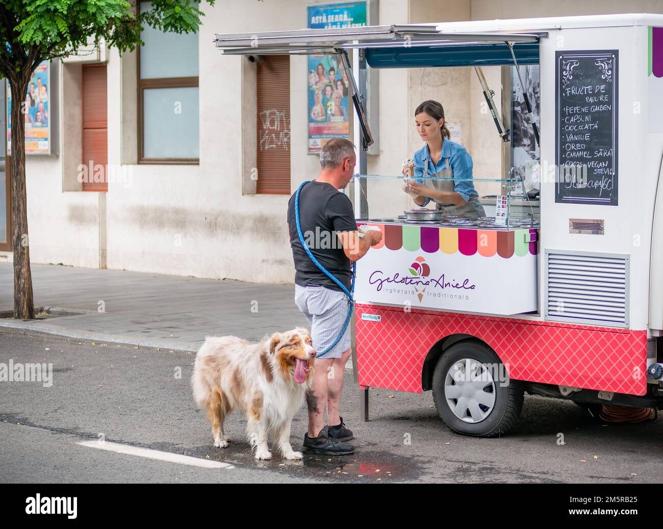 Bucarest, Roumanie - août 2022: Homme avec un chien d'animal achetant de la crème glacée d'un vendeur de rue de camion mobile dans le centre de Bucarest. Banque D'Images