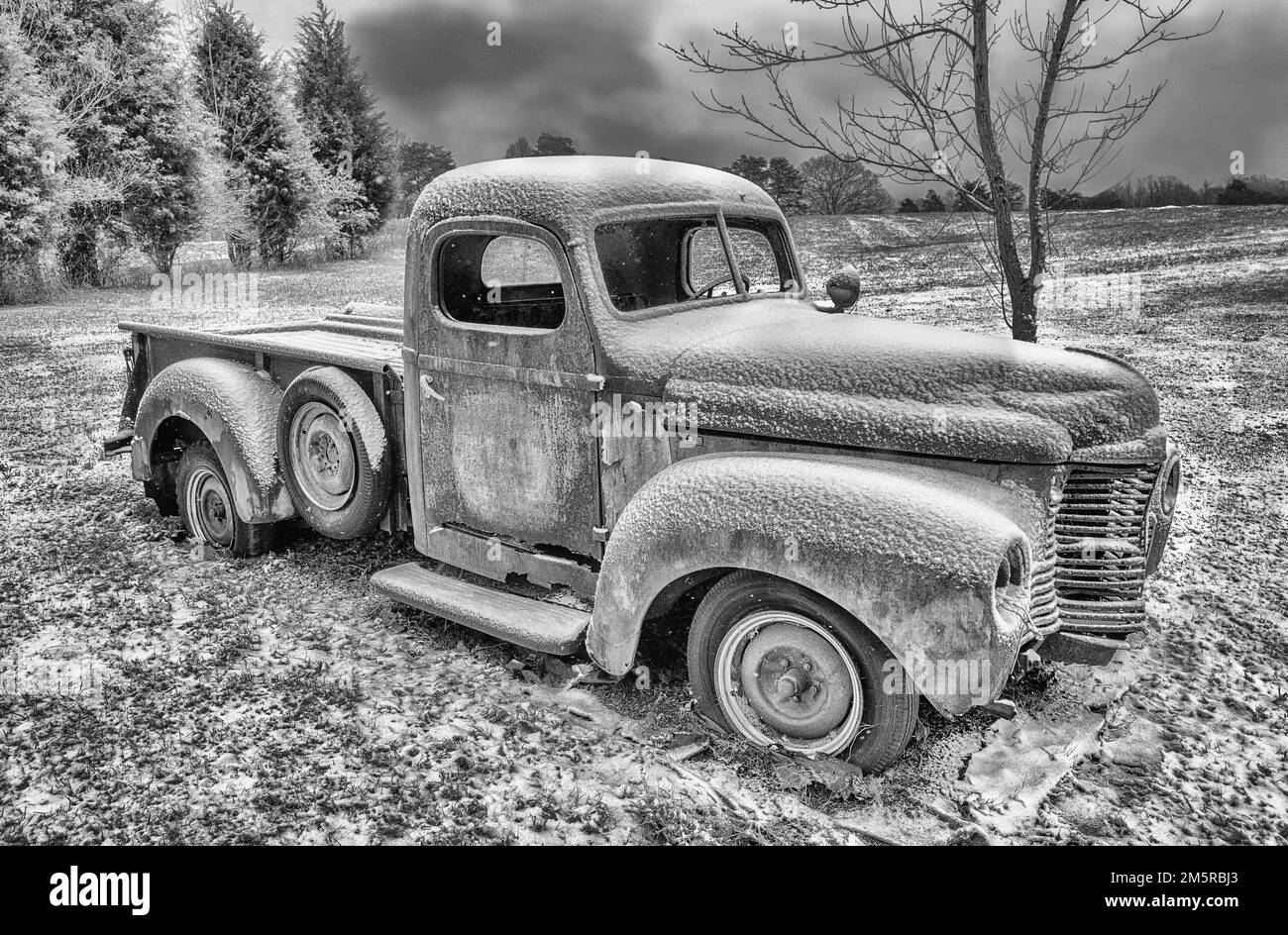 Une photo en noir et blanc d'un ancien pick-up IH de l'époque 1940s abandonné dans un champ enneigé. Banque D'Images