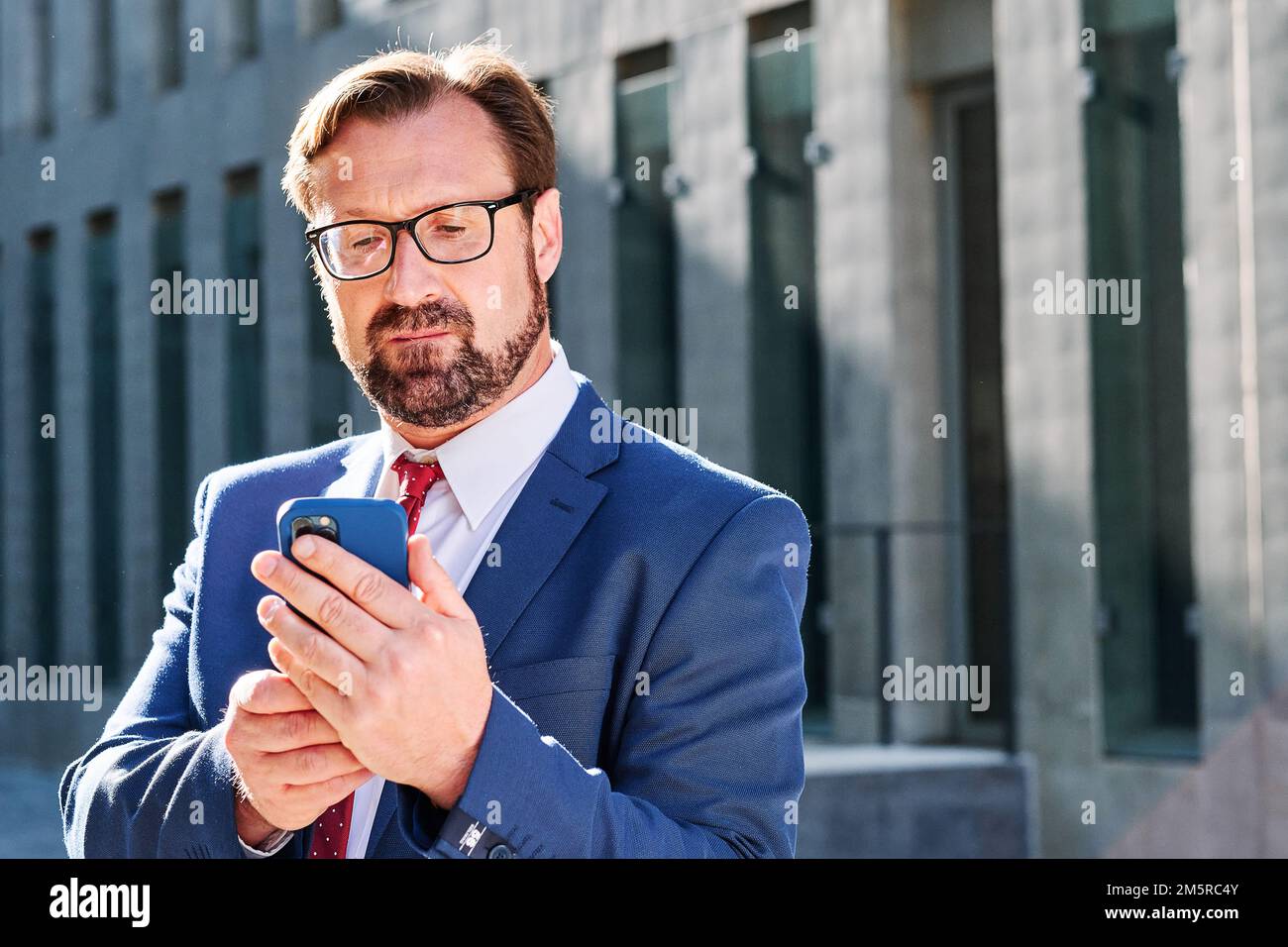 Homme d'affaires concentré utilisant le mobile à l'extérieur Banque D'Images