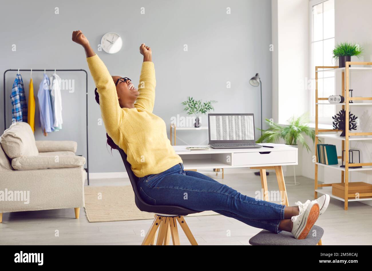 Heureuse et excitée femme levant les mains et criant avec joie célébrant des affaires en ligne réussies. Banque D'Images