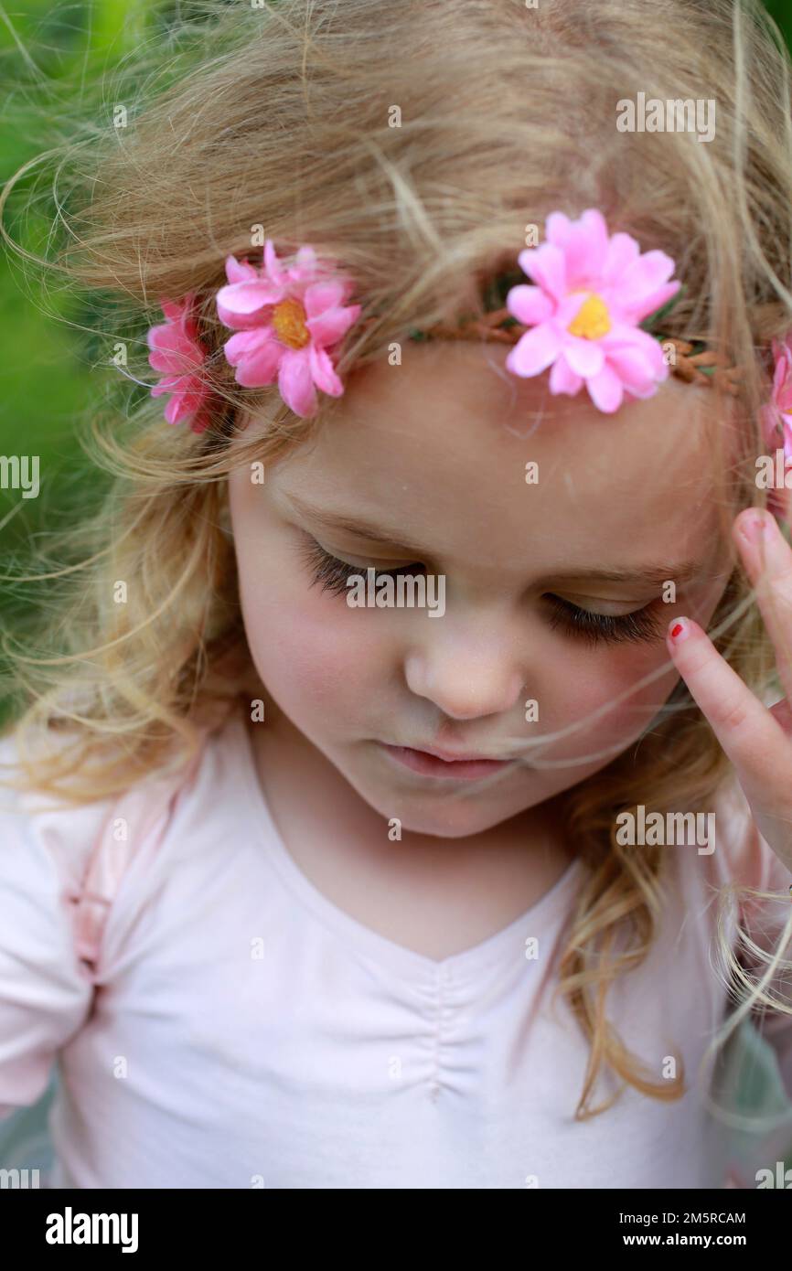 jeune fille de 4 ans avec un bandeau à fleurs roses. Banque D'Images