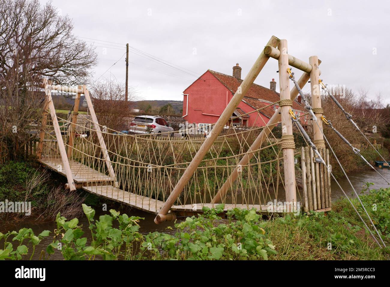 Décembre 2022 - Pont suspendu privé en bois sur la rivière Yeo, sur le côté sud du village de Cheddar, dans le Somerset, Angleterre, Royaume-Uni. Banque D'Images