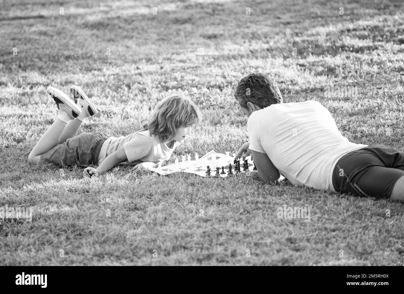famille heureuse de père et fils enfant jouant aux échecs sur l'herbe verte dans le parc extérieur, famille Banque D'Images
