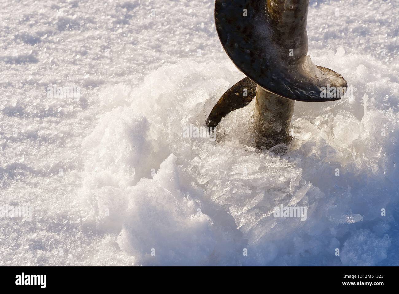 Concept de pêche d'hiver. Pêcheur faisant le trou dans la glace par la vis à glace Banque D'Images