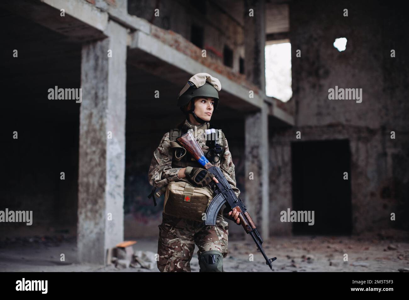 Femme ukrainienne Soldat avec une arme dans ses mains dans un bâtiment détruit. Guerre entre l'Ukraine et la Russie. Banque D'Images