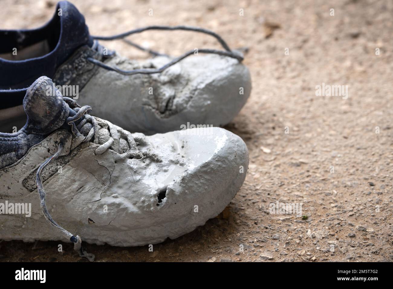 Chaussures fortement tachées dans la peinture grise sur un asphalte Banque D'Images