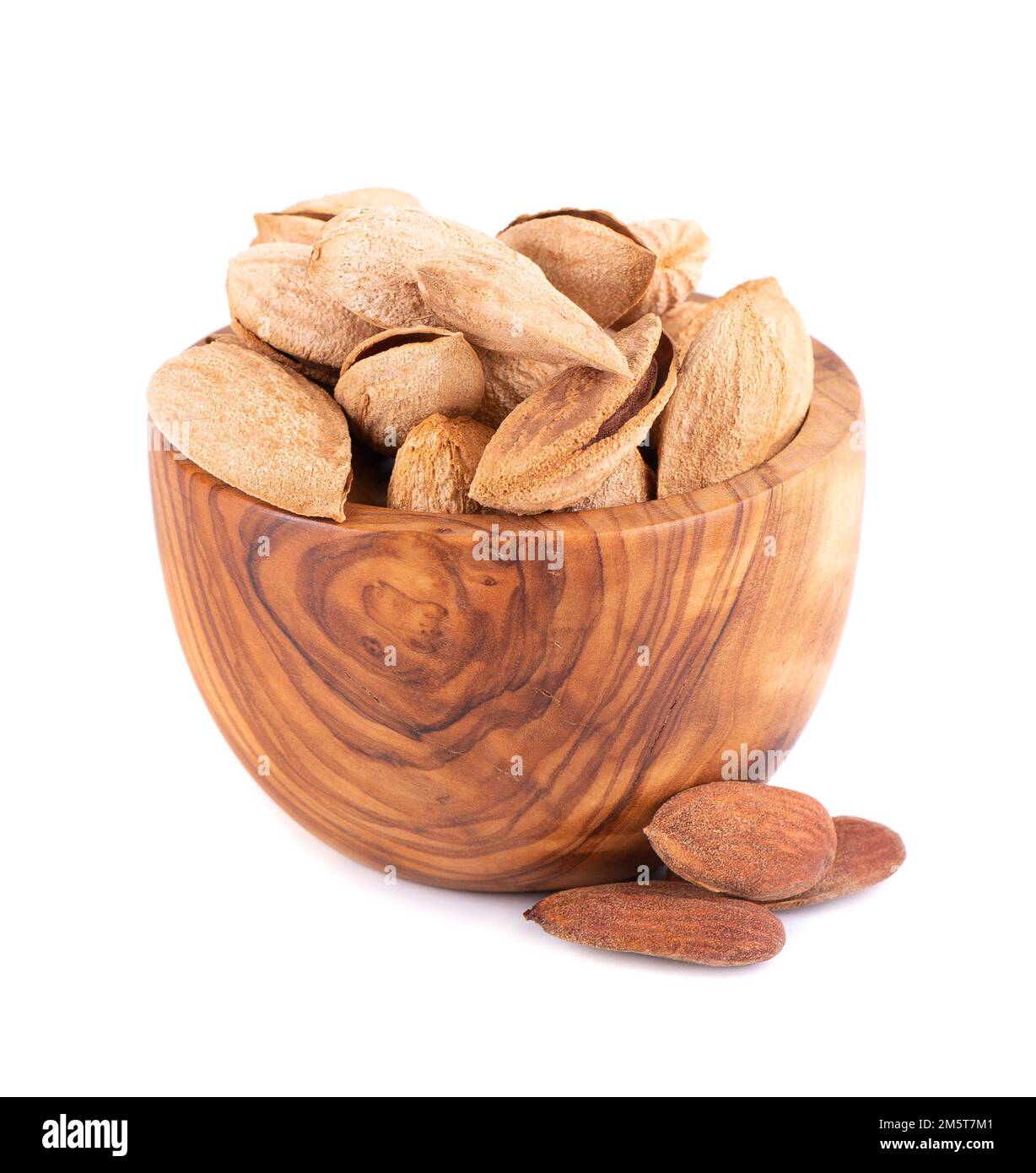 Amandes de montagne dans un bol en bois, isolées sur fond blanc. Amandes sauvages ouzbèkes Banque D'Images