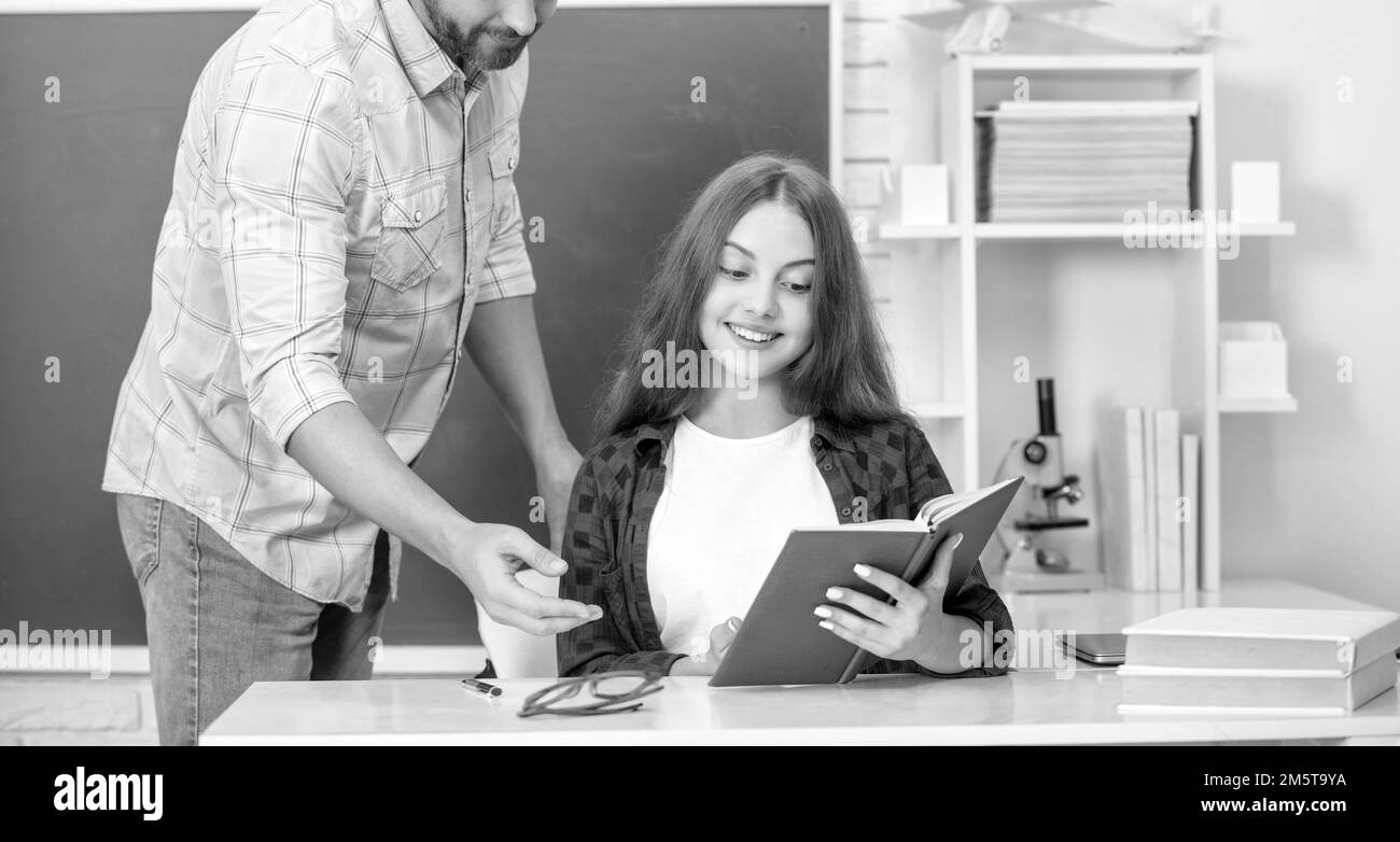 bonne fille de l'adolescence et petit homme enseignant dans l'école secondaire avec cahier à tableau noir, école Banque D'Images