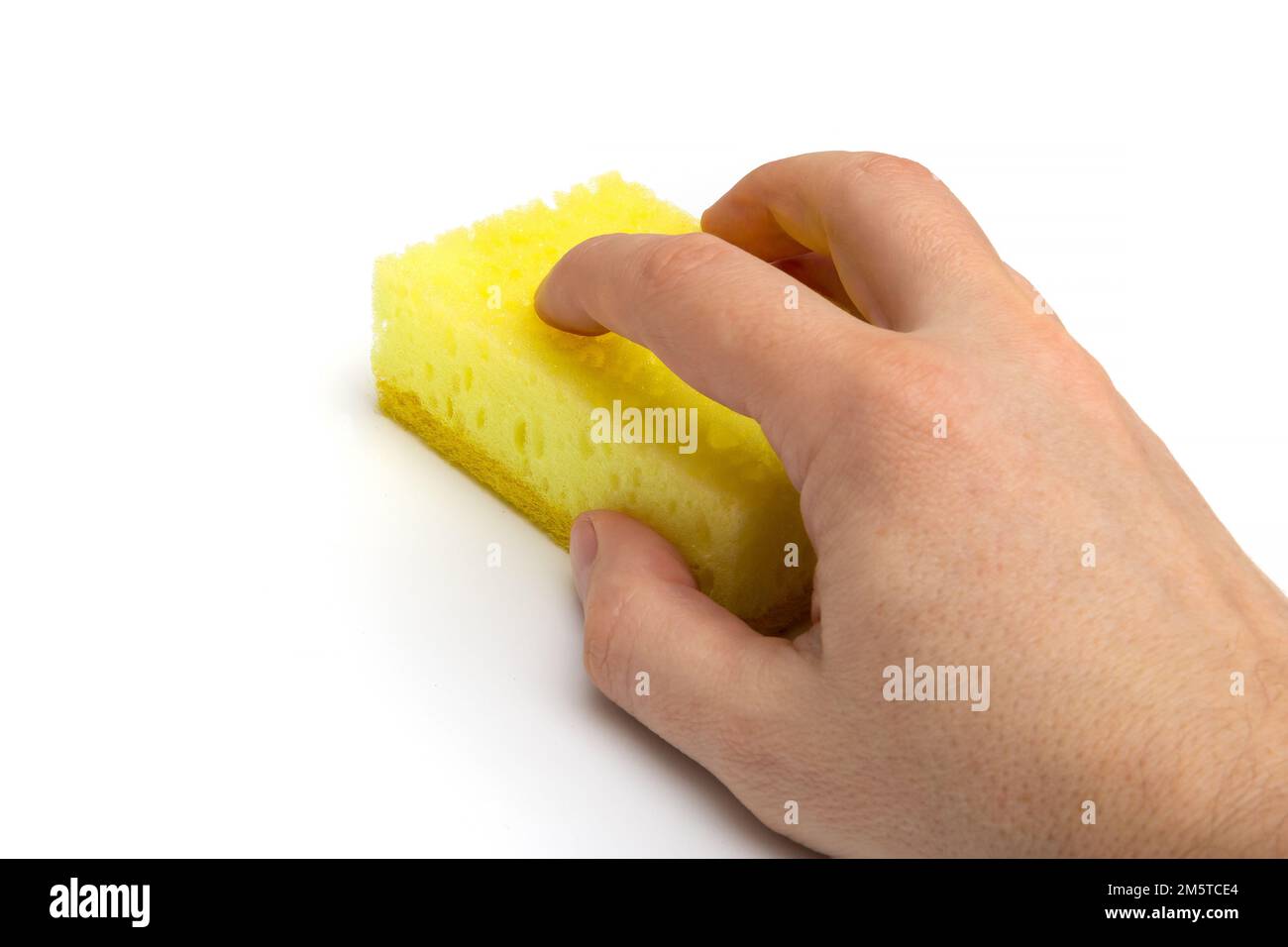 Main avec une éponge de cuisine jaune isolée sur fond blanc, vue de côté rapprochée Banque D'Images Main avec une éponge de cuisine jaune isolée sur fond blanc, vue de côté rapprochée Banque D'Images