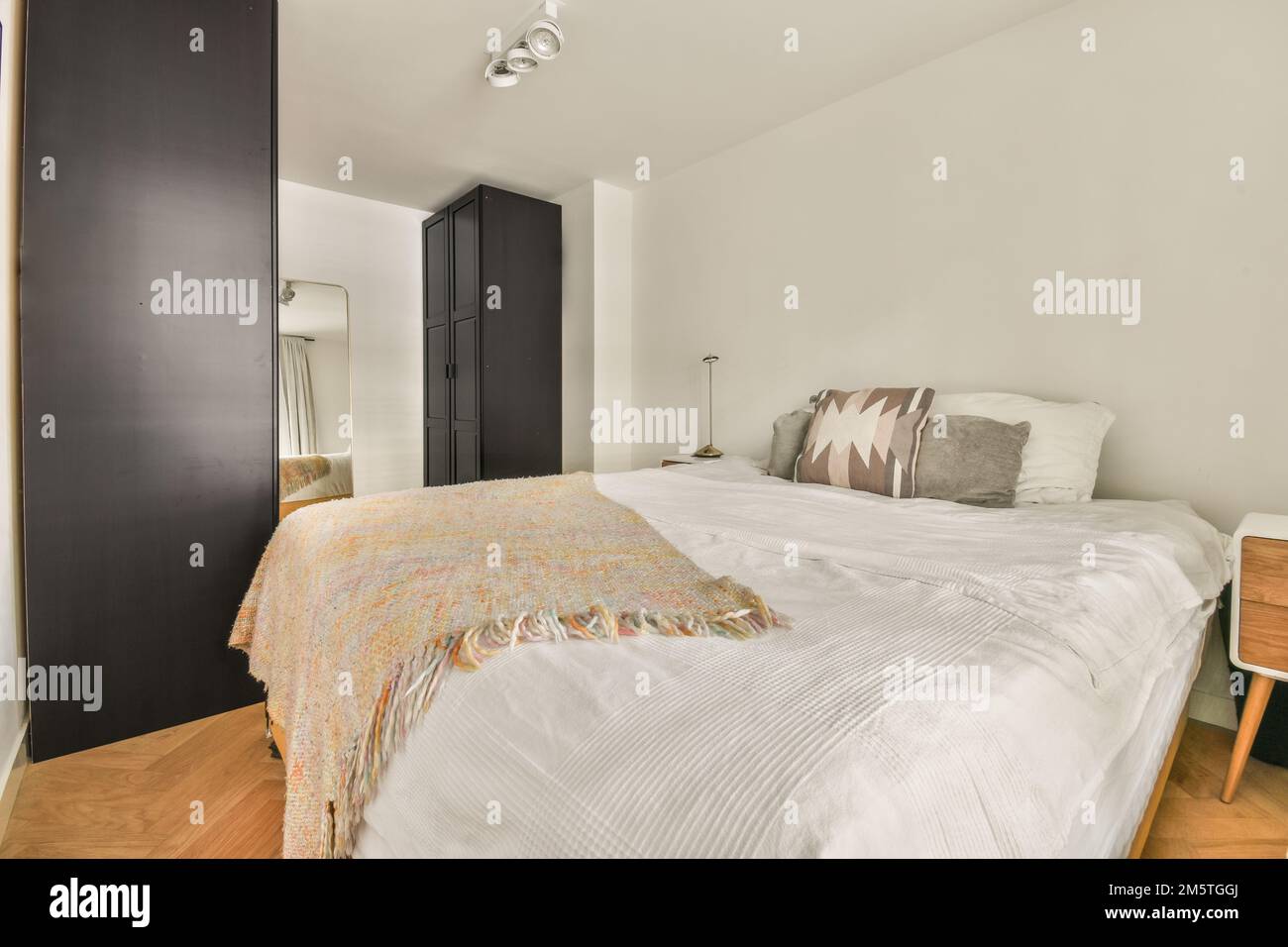 une chambre avec un lit, une commode et un miroir sur le mur en face du lit est blanche et noire Banque D'Images