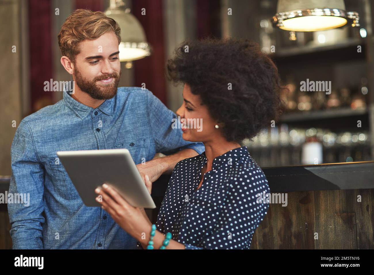 Installation d'une application pour leurs serveurs. un jeune homme et une jeune femme utilisant une tablette numérique ensemble dans un café. Banque D'Images