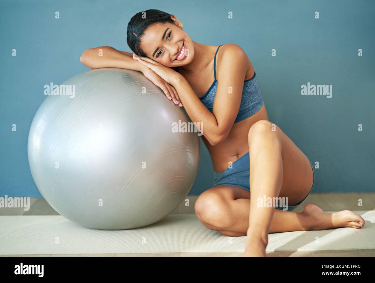 Tous les jours est une bonne journée à l'entraînement. une jeune femme sportive penchée contre une balle pilates. Banque D'Images