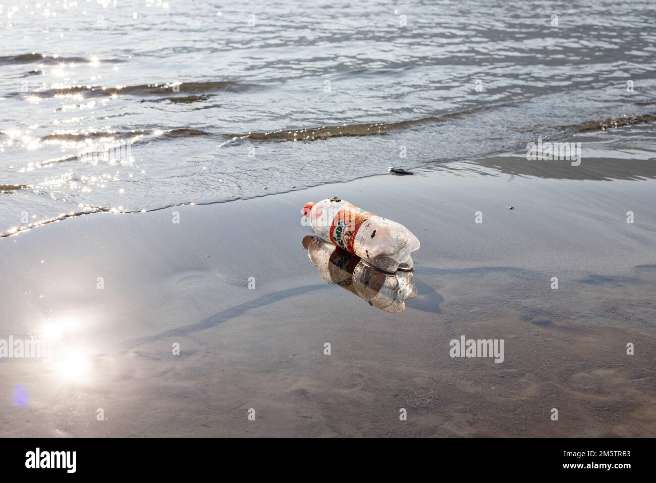 Une bouteille en plastique se trouve sur la plage, polluant la mer et la mer Banque D'Images Une bouteille en plastique se trouve sur la plage, polluant la mer et la mer Banque D'Images