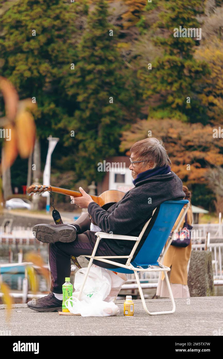 Un vieil homme jouant de la guitare par le lac Ashi, Hakone Banque D'Images