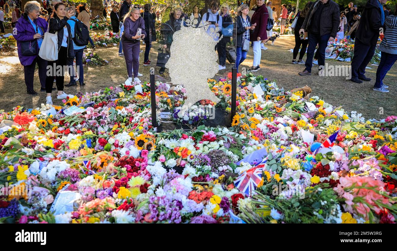 Une silhouette de verre et des hommages aux fleurs avec des amateurs de tournants visitent Green Park après la mort de la reine Elizabeth II, Londres, Royaume-Uni Banque D'Images