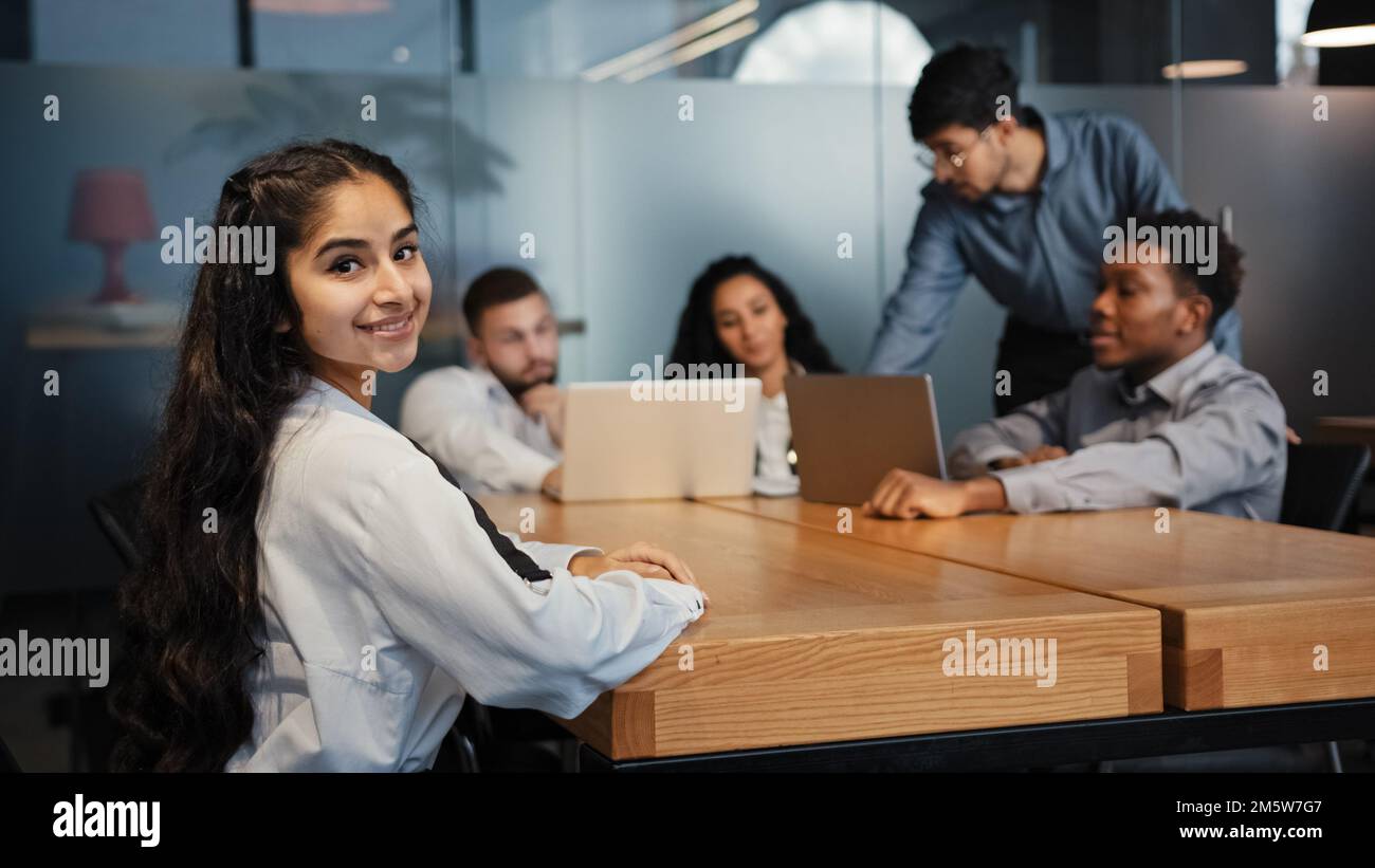 Femme d'affaires ethnique indienne regardant la caméra posant au bureau sur un fond flou de brainstorming divers employés de bureau multiethnique multiraciale Banque D'Images