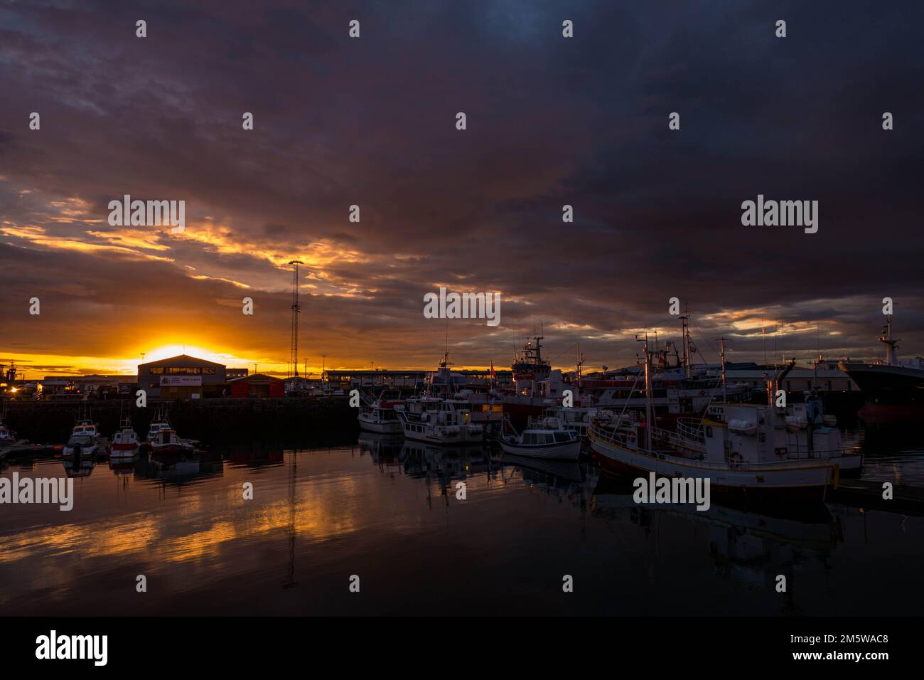 Une belle photo d'un coucher de soleil sur un port avec des navires amarrés et des bateaux Banque D'Images