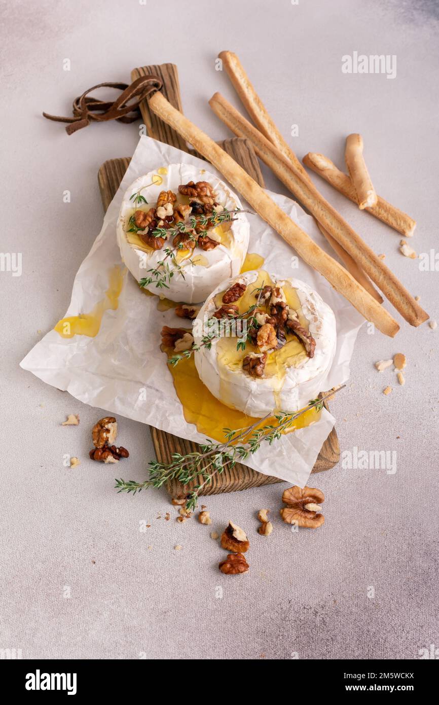 Repas gastronomique de brie blanc ou de camembert au thym, noix, miel et bâtonnets de pain de grissini pour un dîner savoureux Banque D'Images