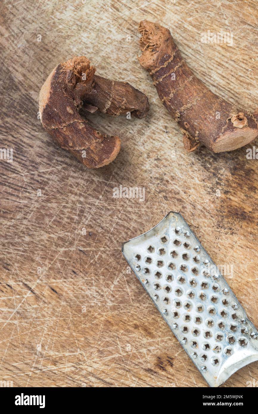 Préparation alimentaire rustique : morceaux de racine de gingembre séchés et râpe sur fond de bois. Banque D'Images