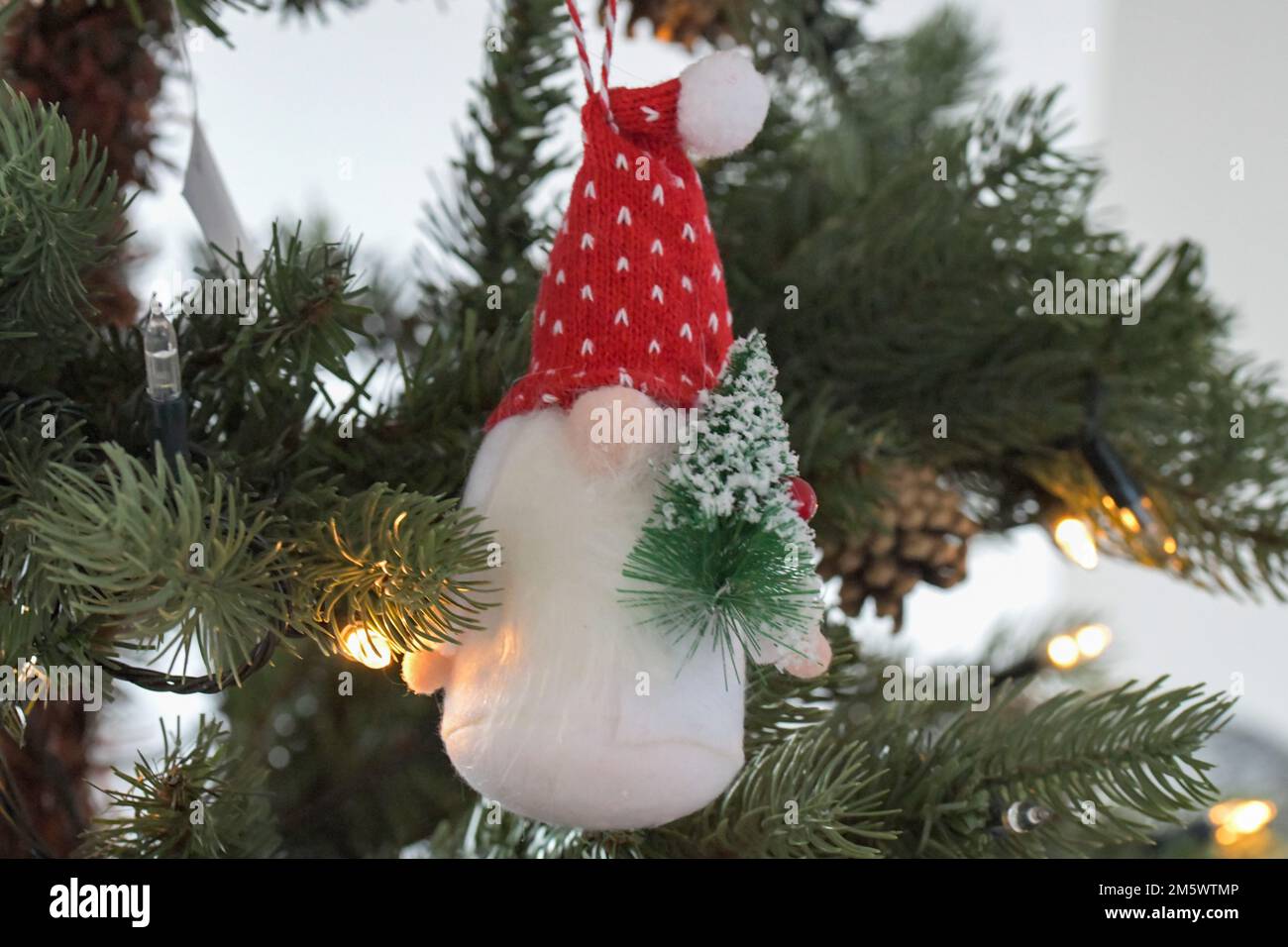 Un arbre de Noël, Gonk, ornement, suspendu d'un arbre de Noël tenant un arbre de Noël miniature avec un chapeau rouge festif Banque D'Images