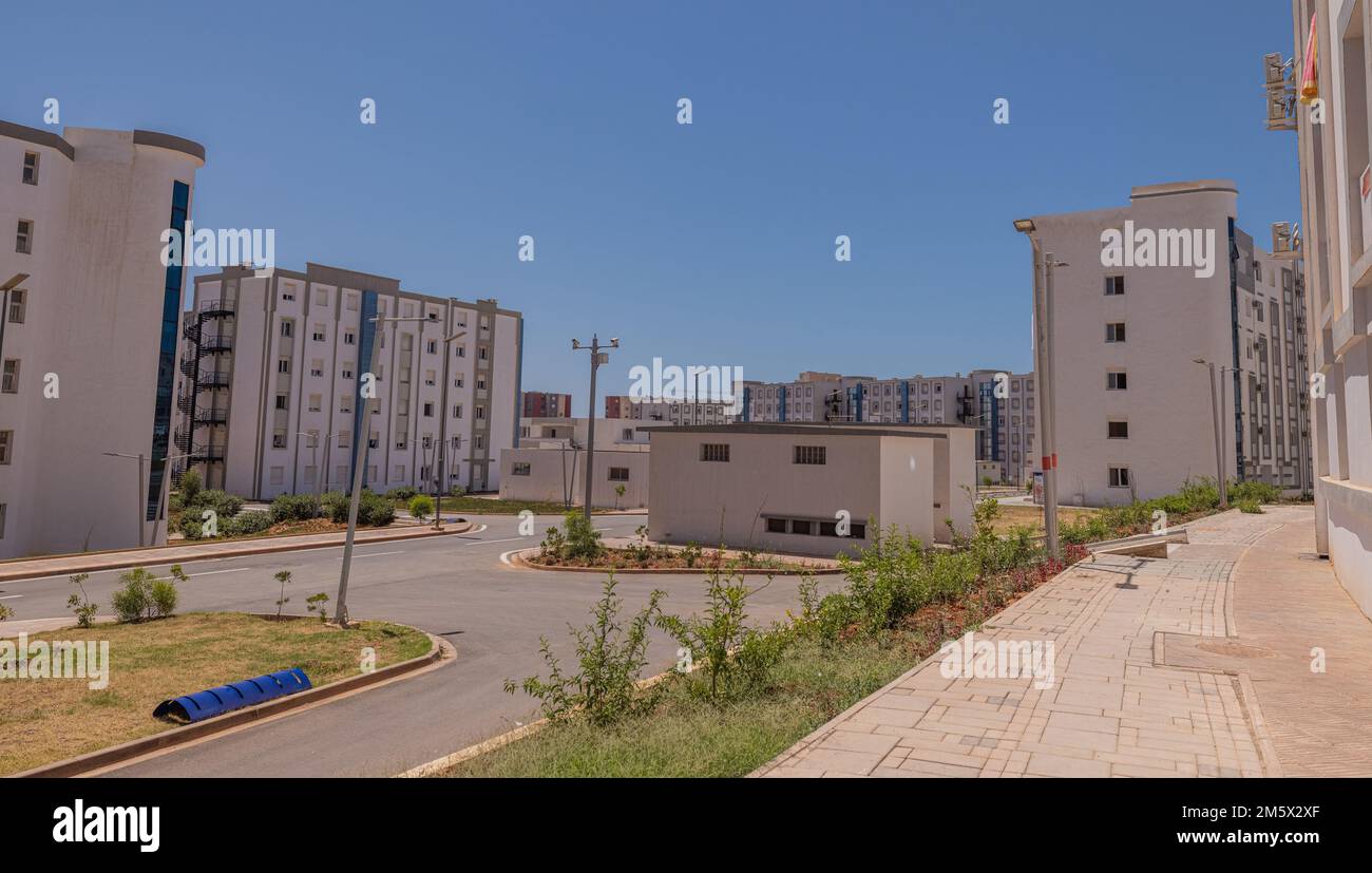 Nouveau quartier résidentiel à Oran, Algérie, avec une multitude de nouvelles maisons ou de blocs de ville au soleil chaud. Une certaine végétation est visible autour. Banque D'Images