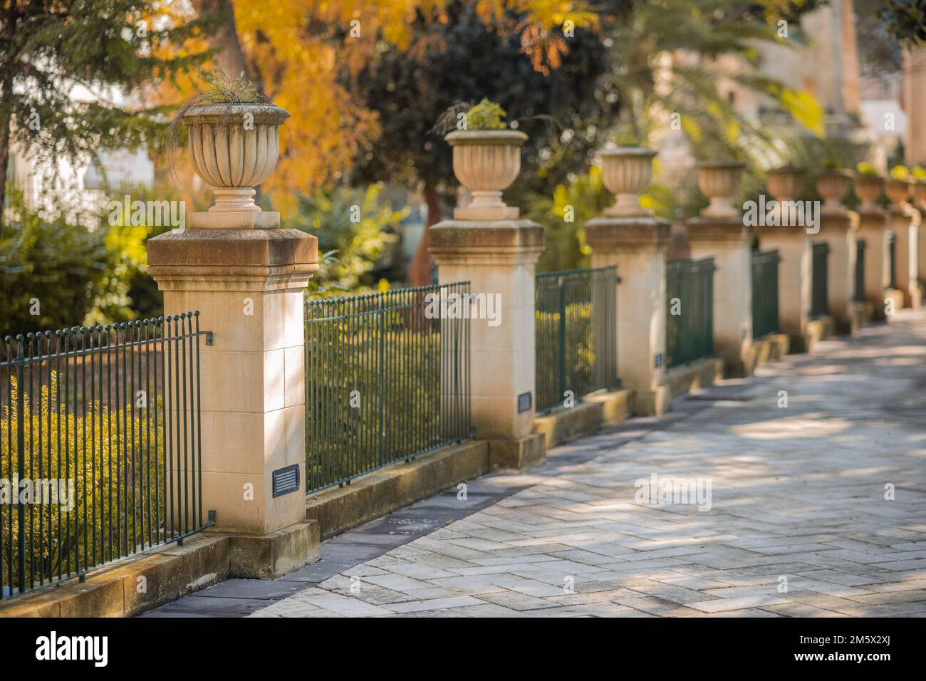Jardins universitaires d'Argotti à la Valette, Malte, par une journée ensoleillée. Vue sur une rangée de piliers avec clôture. Banque D'Images