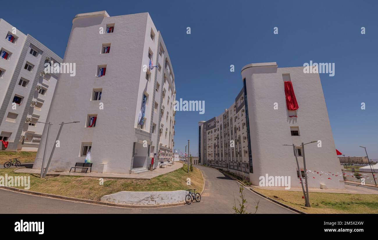 Nouveau quartier résidentiel à Oran, Algérie, avec une multitude de nouvelles maisons ou de blocs de ville au soleil chaud. Une certaine végétation est visible autour. Banque D'Images