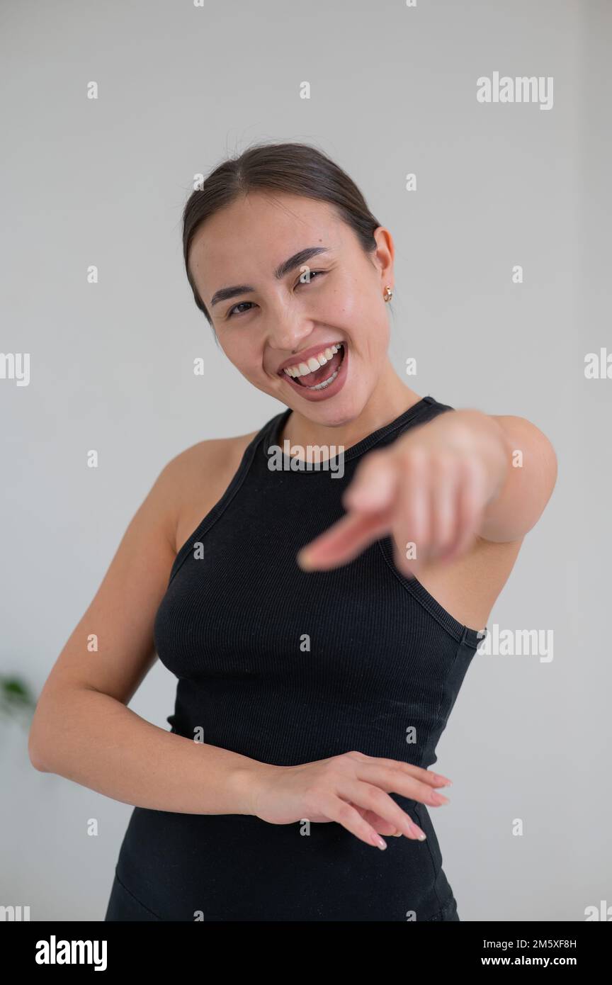 Femme asiatique souriante pointant son doigt sur fond blanc. Banque D'Images Femme asiatique souriante pointant son doigt sur fond blanc. Banque D'Images