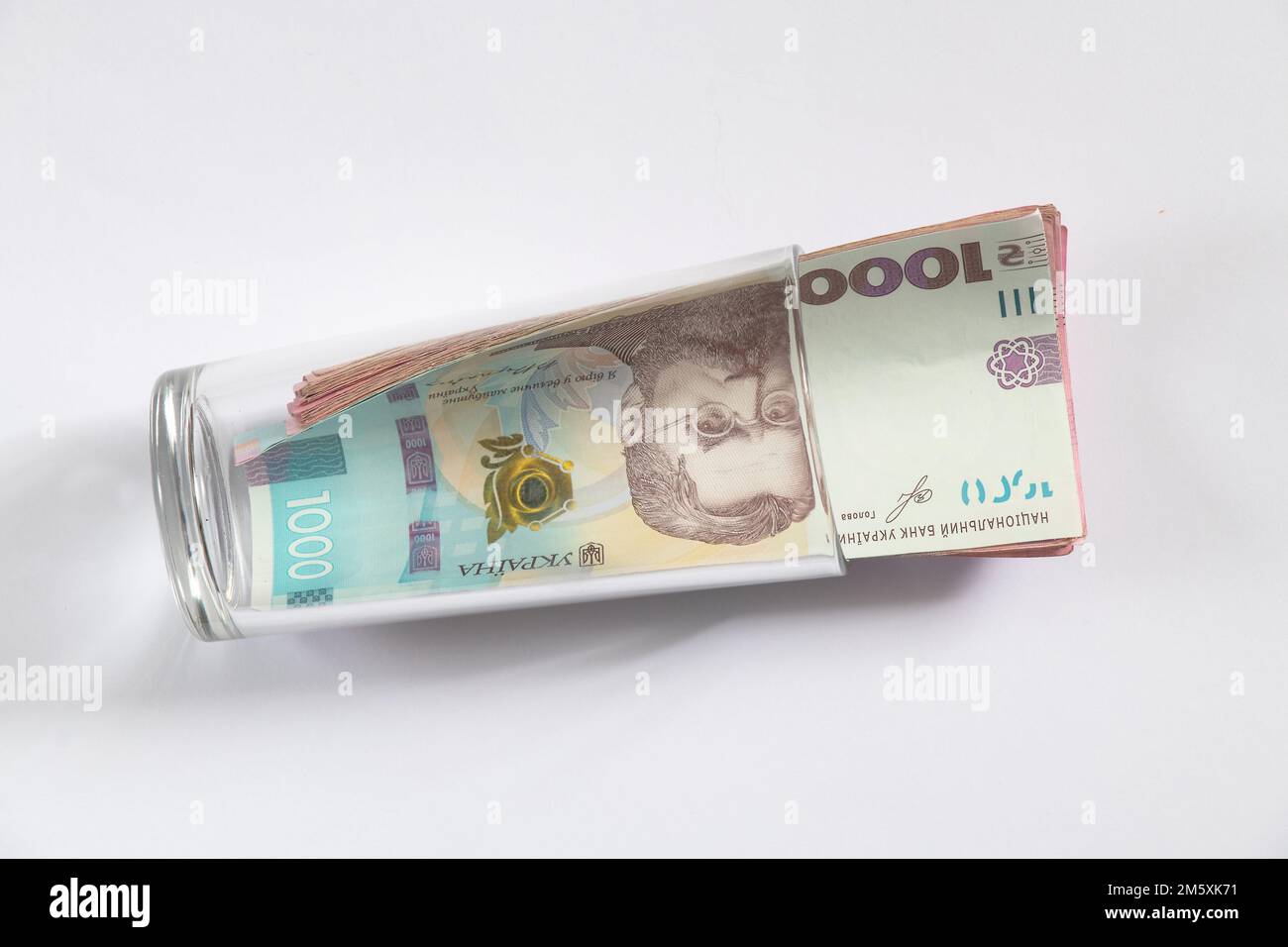 la hryvnia et le dollar se trouvent dans une tasse de verre sur un fond blanc Banque D'Images la hryvnia et le dollar se trouvent dans une tasse de verre sur un fond blanc Banque D'Images