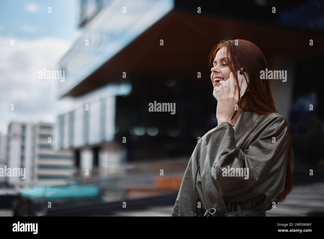 Femme d'affaires parlant au téléphone et souriant devant les bâtiments de la ville, le concept de la technologie et le développement des affaires en ligne Banque D'Images