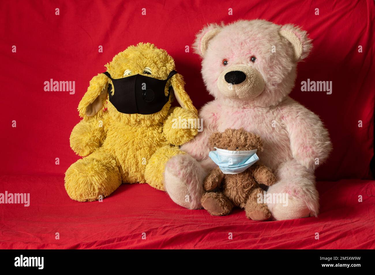 les jouets doux en peluche des enfants dans le masque médical se trouvent sur le canapé rouge, les soins de santé et la médecine, la morbidité des enfants Banque D'Images