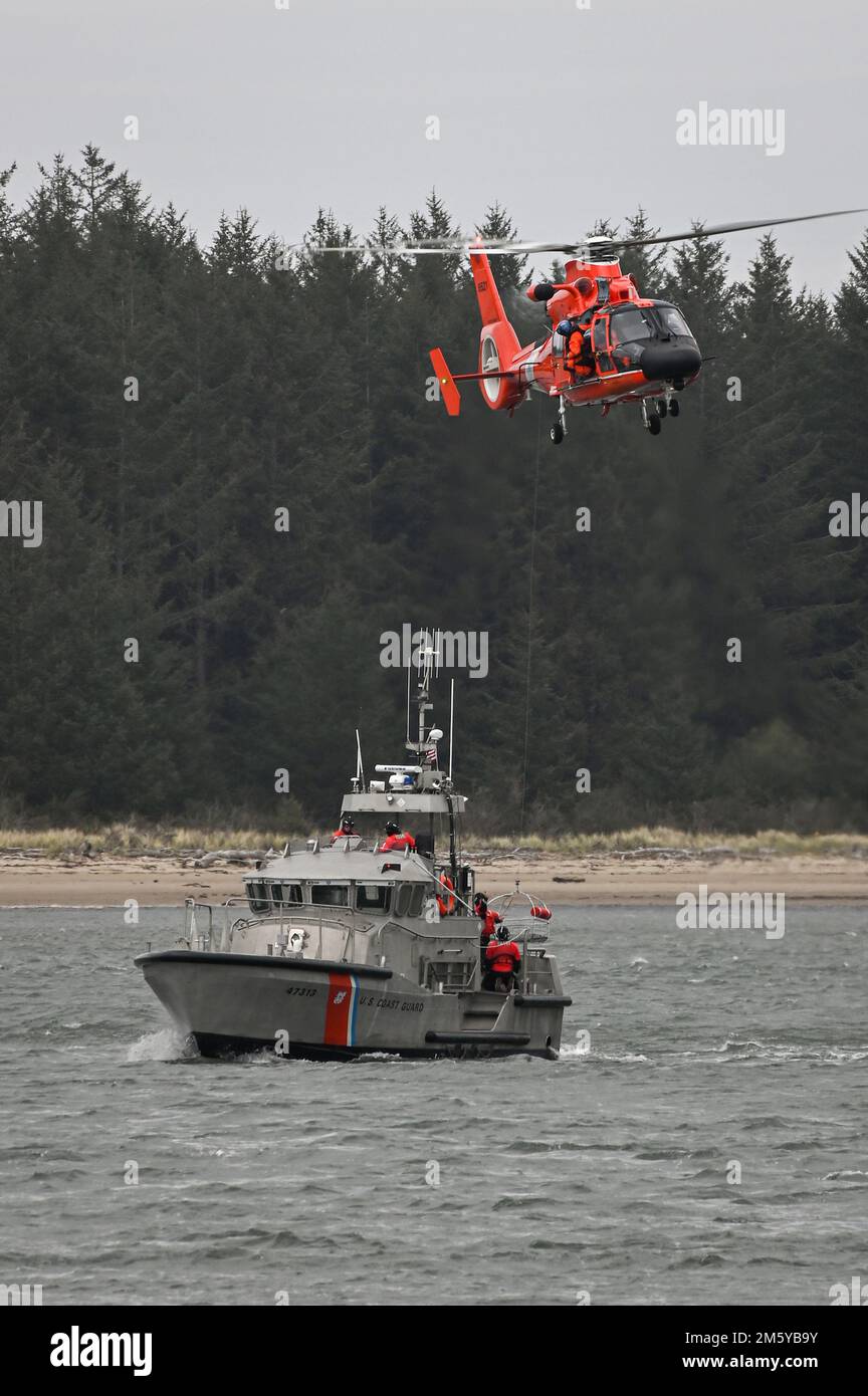 Un équipage à bord d'un hélicoptère MH-65E Dolphin du secteur North Bend de la Garde côtière effectue une formation de levage avec un équipage à bord d'un canot de sauvetage à moteur de 47 pieds de la station de la Garde côtière, sur la rivière Umpqua, tout en transitant près de la baie de Winchester, en Oregon, en 14 mars 2015. Les équipages s'entraînent régulièrement avec les stations de bateaux de sauvetage pour maintenir leurs compétences en cas d'intervention d'urgence. (É.-U. Photo de la Garde côtière par l'officier Petty Steve Strohmaier) Banque D'Images