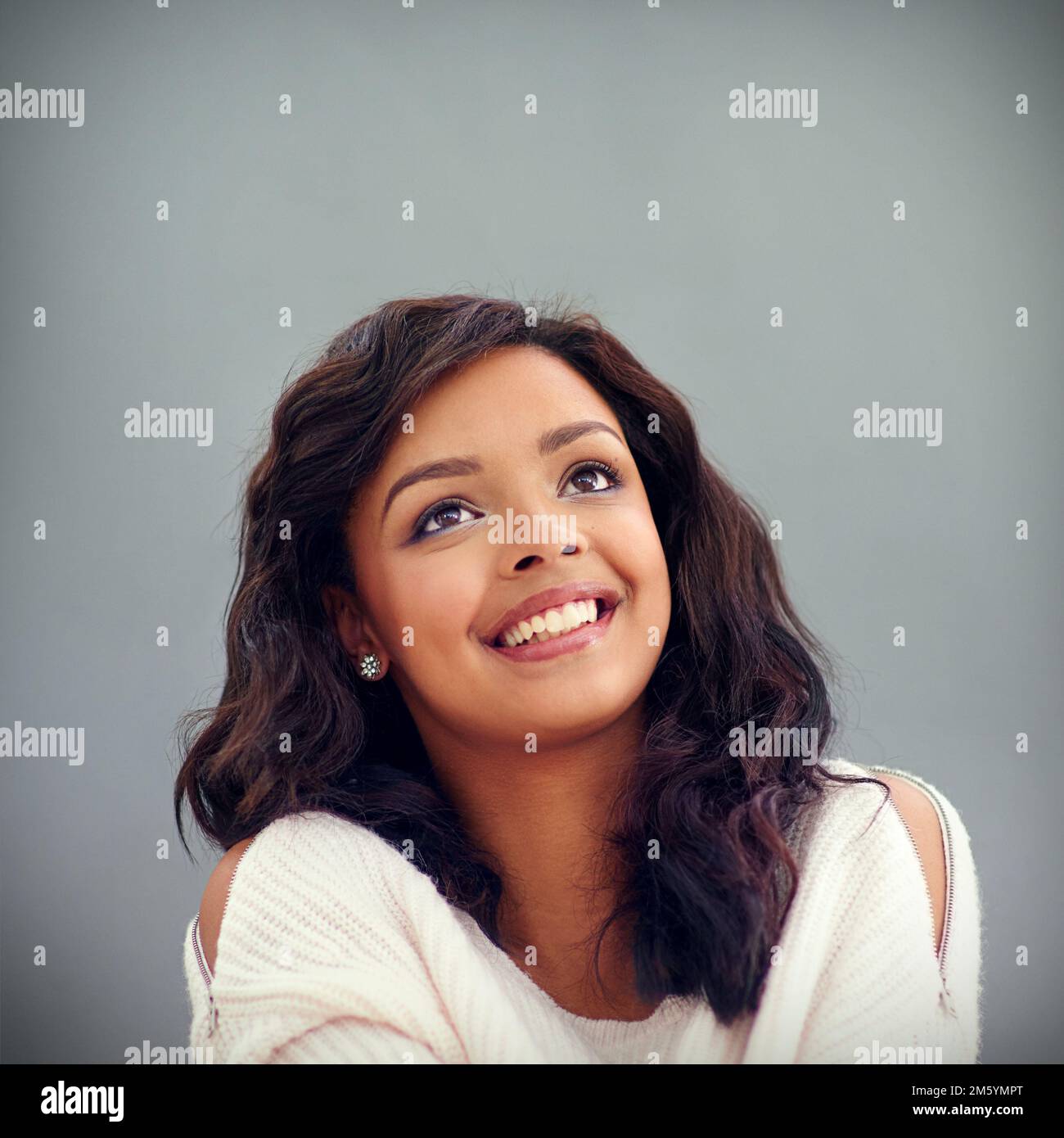 Oh joie. Photo en studio d'une jeune femme attrayante posant sur un fond gris. Banque D'Images