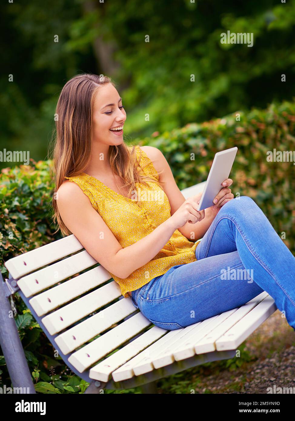 La technologie moderne au contact n'a jamais été aussi simple. une jeune femme utilisant une tablette numérique sur un banc de parc. Banque D'Images