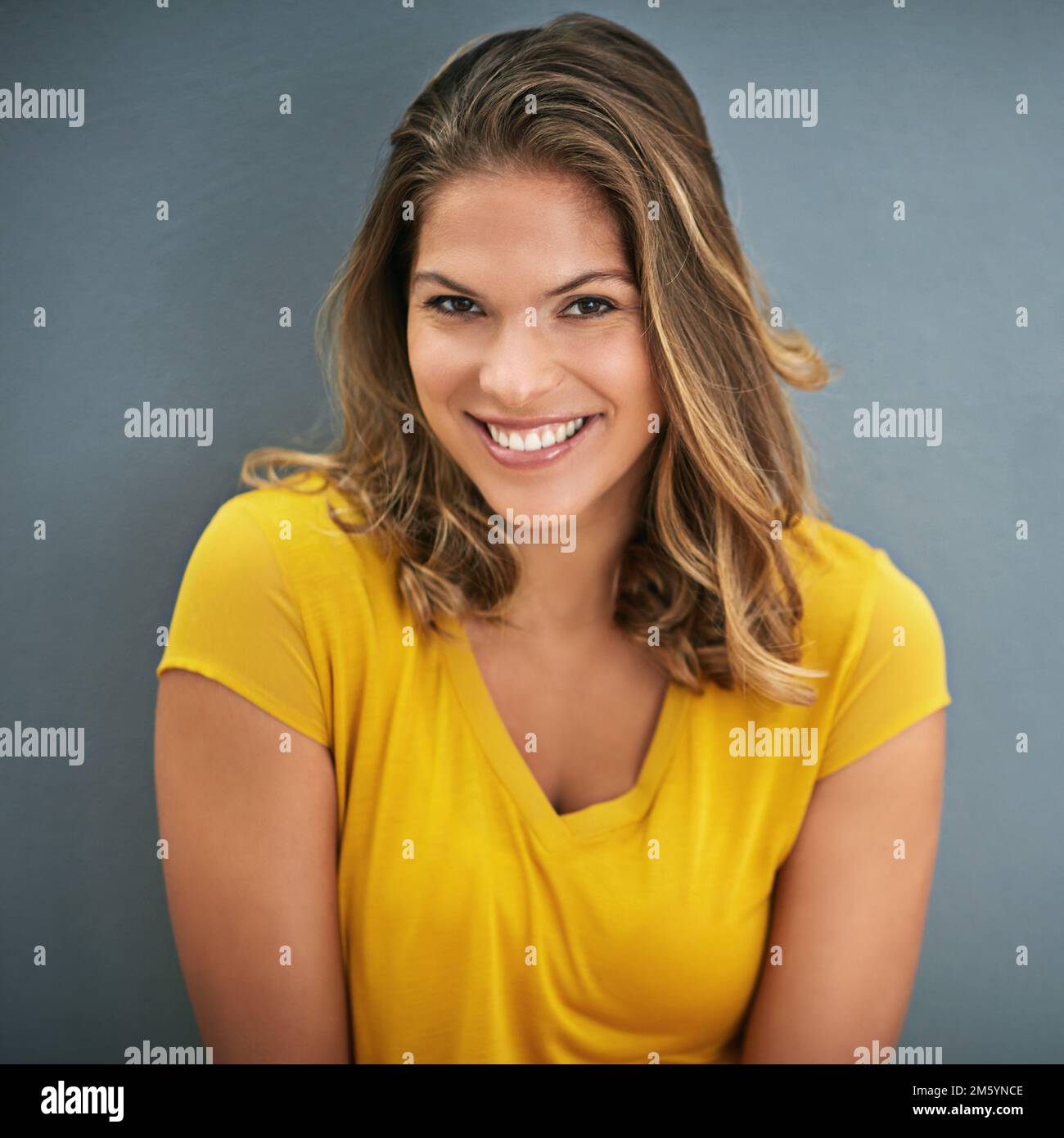 Je ne peux pas le cacher. une jeune femme posant contre un mur gris. Banque D'Images
