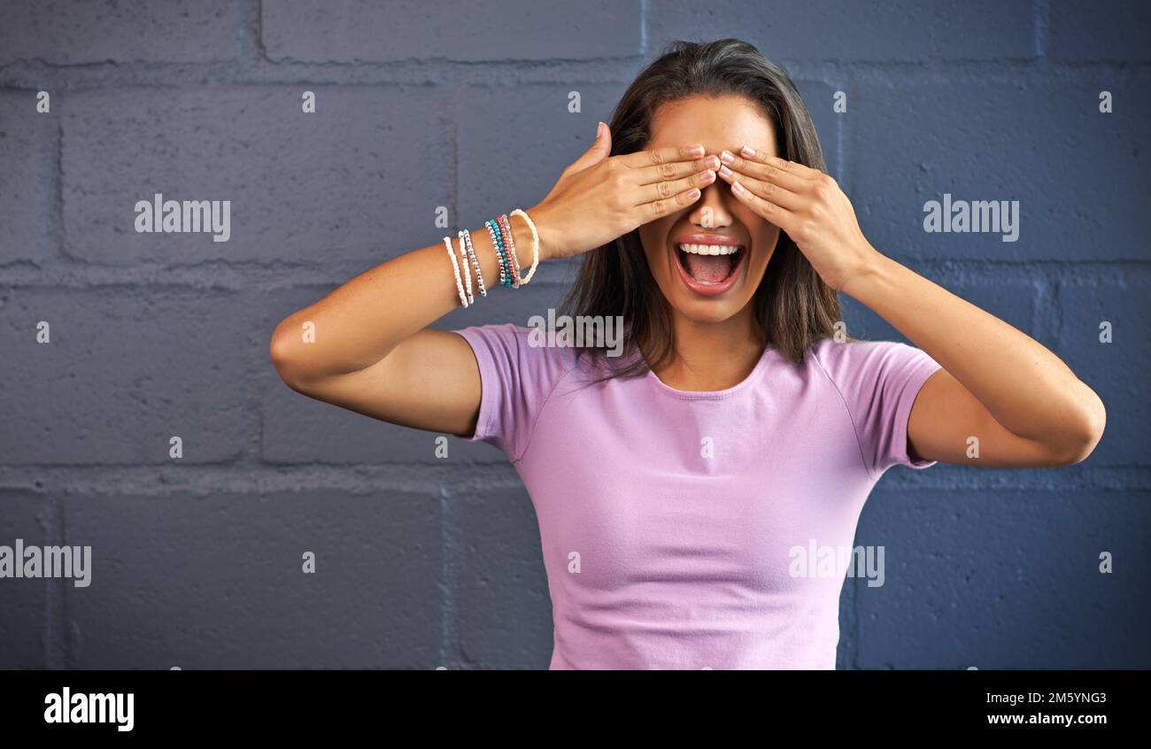 Puis-je ouvrir les yeux maintenant. une jeune femme couvrant ses yeux contre un fond de mur de briques. Banque D'Images